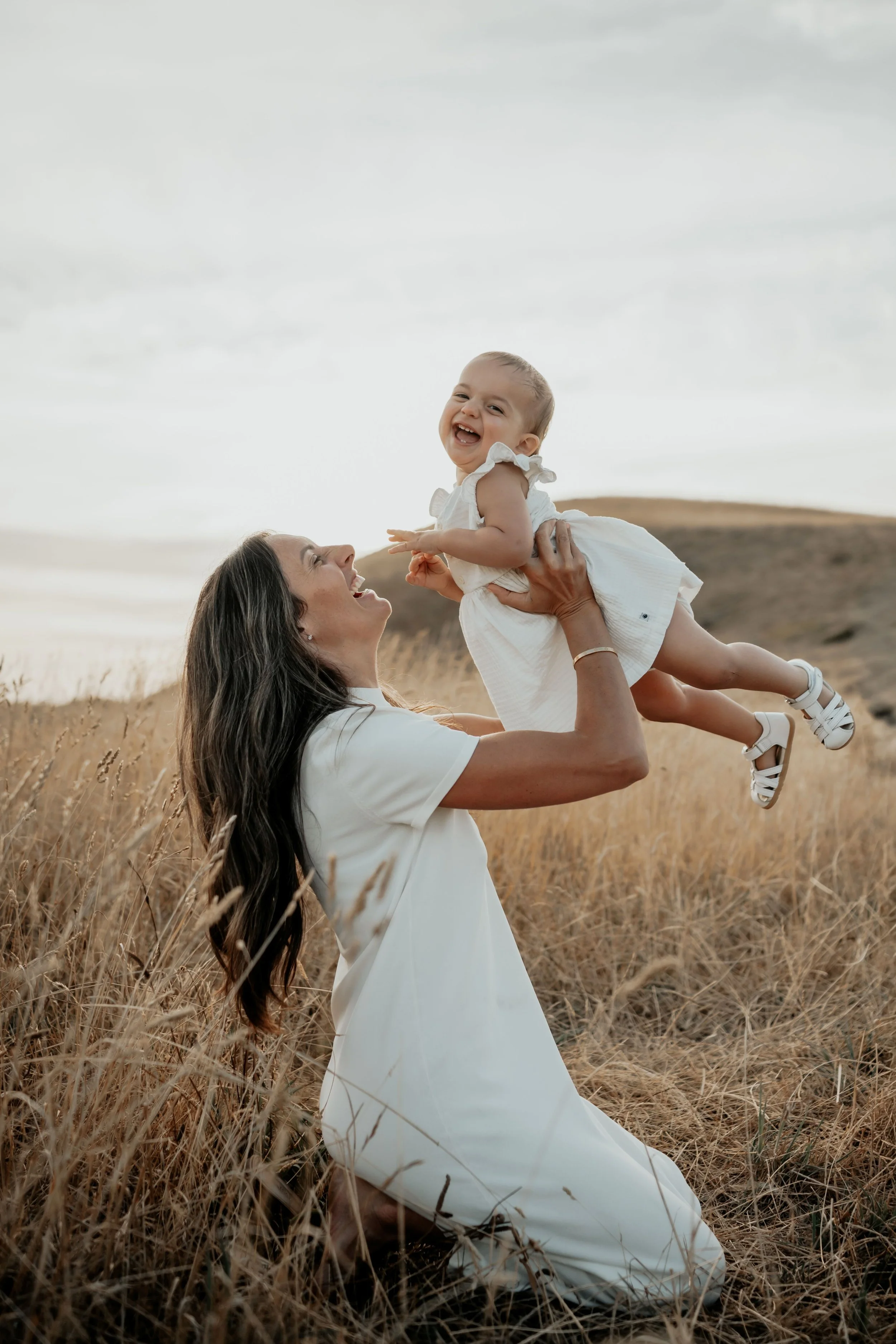 Mother holding her daughter up in the air playing and laughing