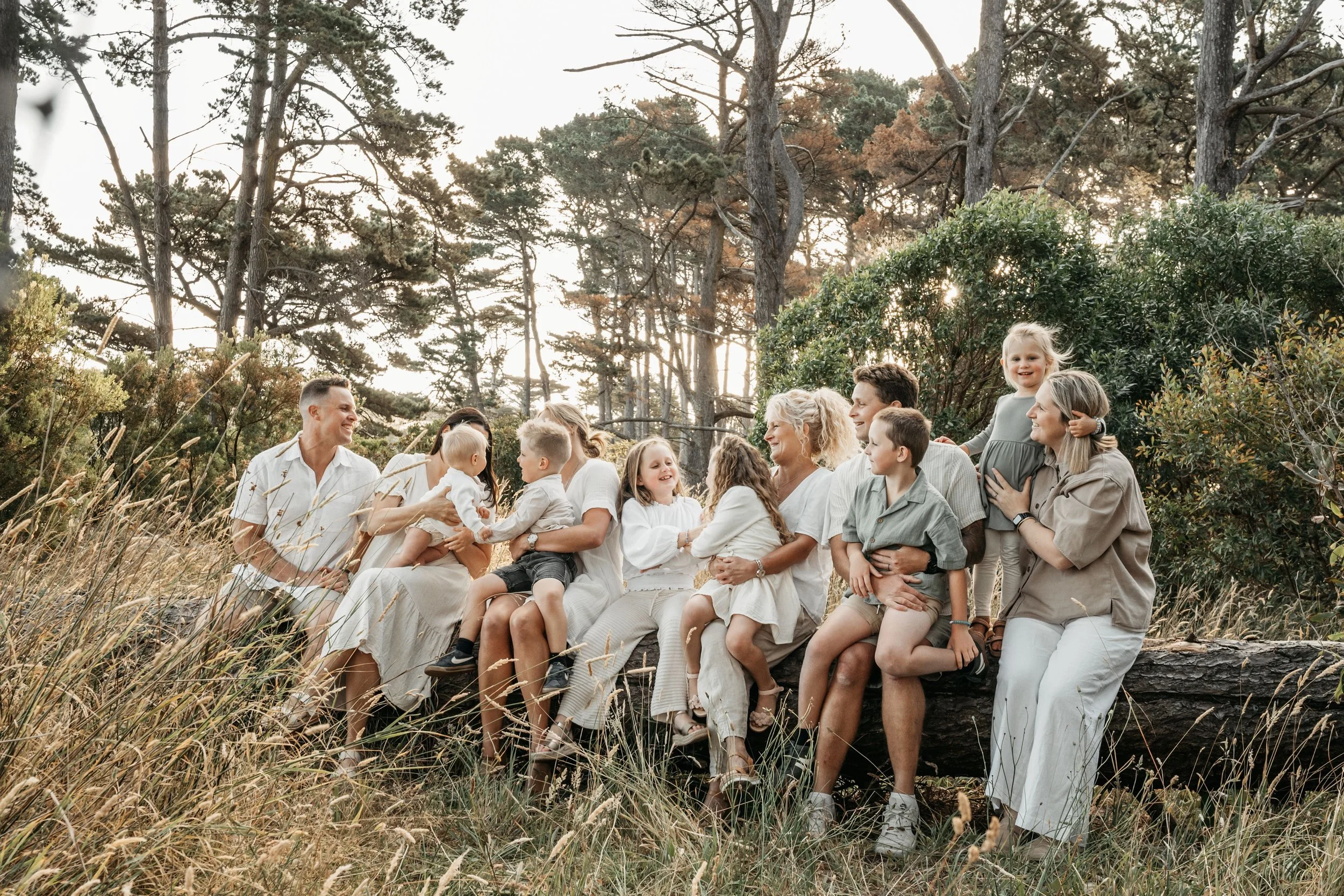 An extended family chat and laugh sitting on a log in the forest