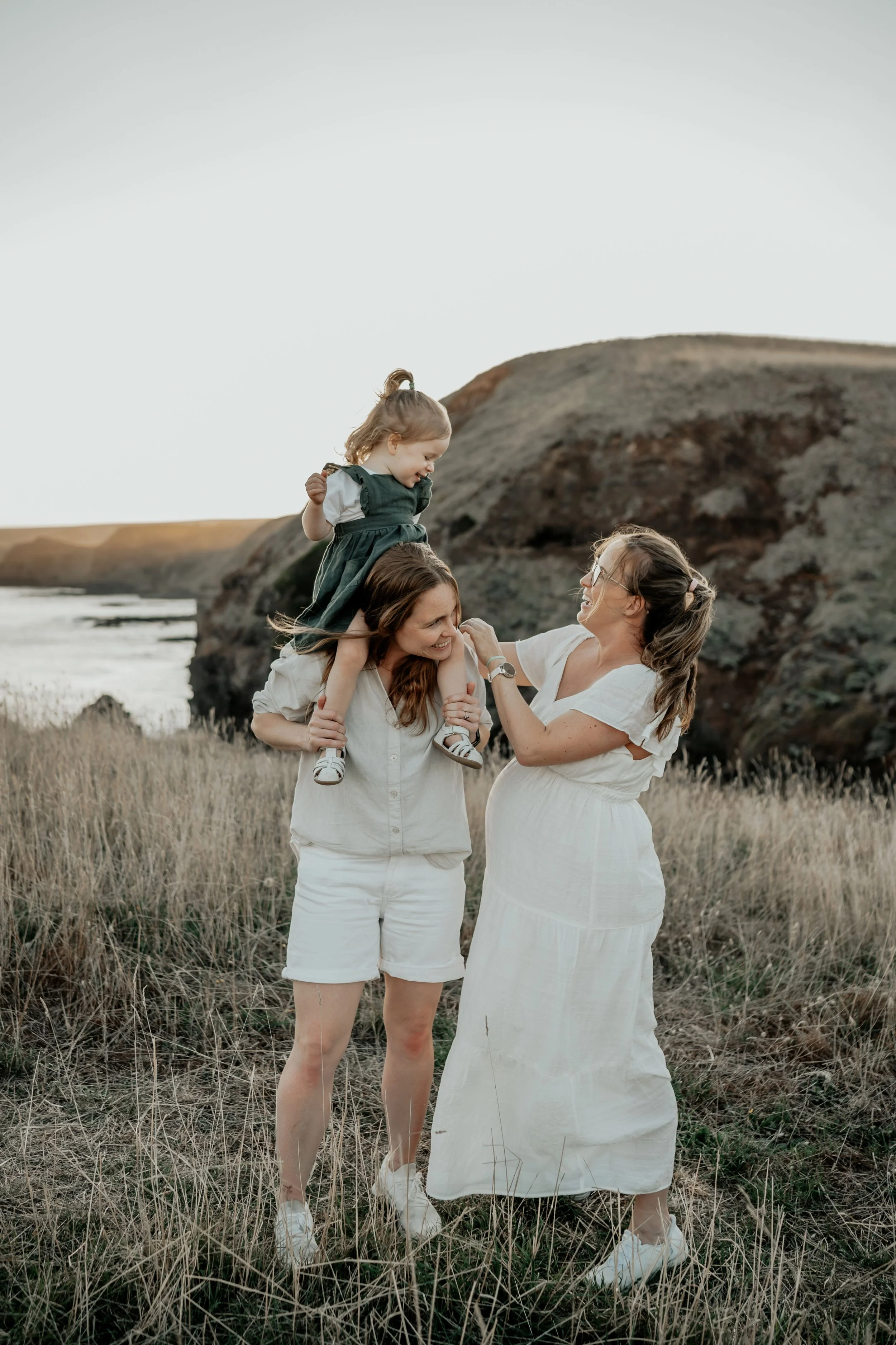 Two mother's and their daughter play and tickle each other