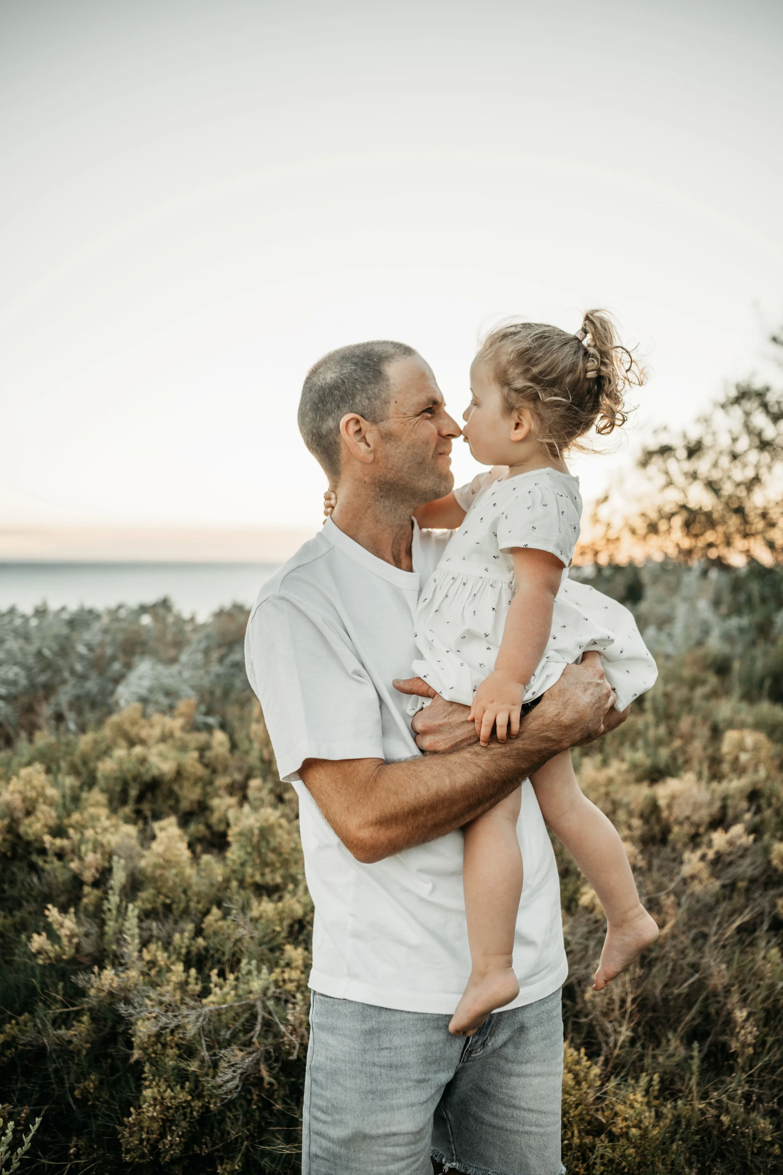 A dad and his daughter, daughter kissing her dad on the nose