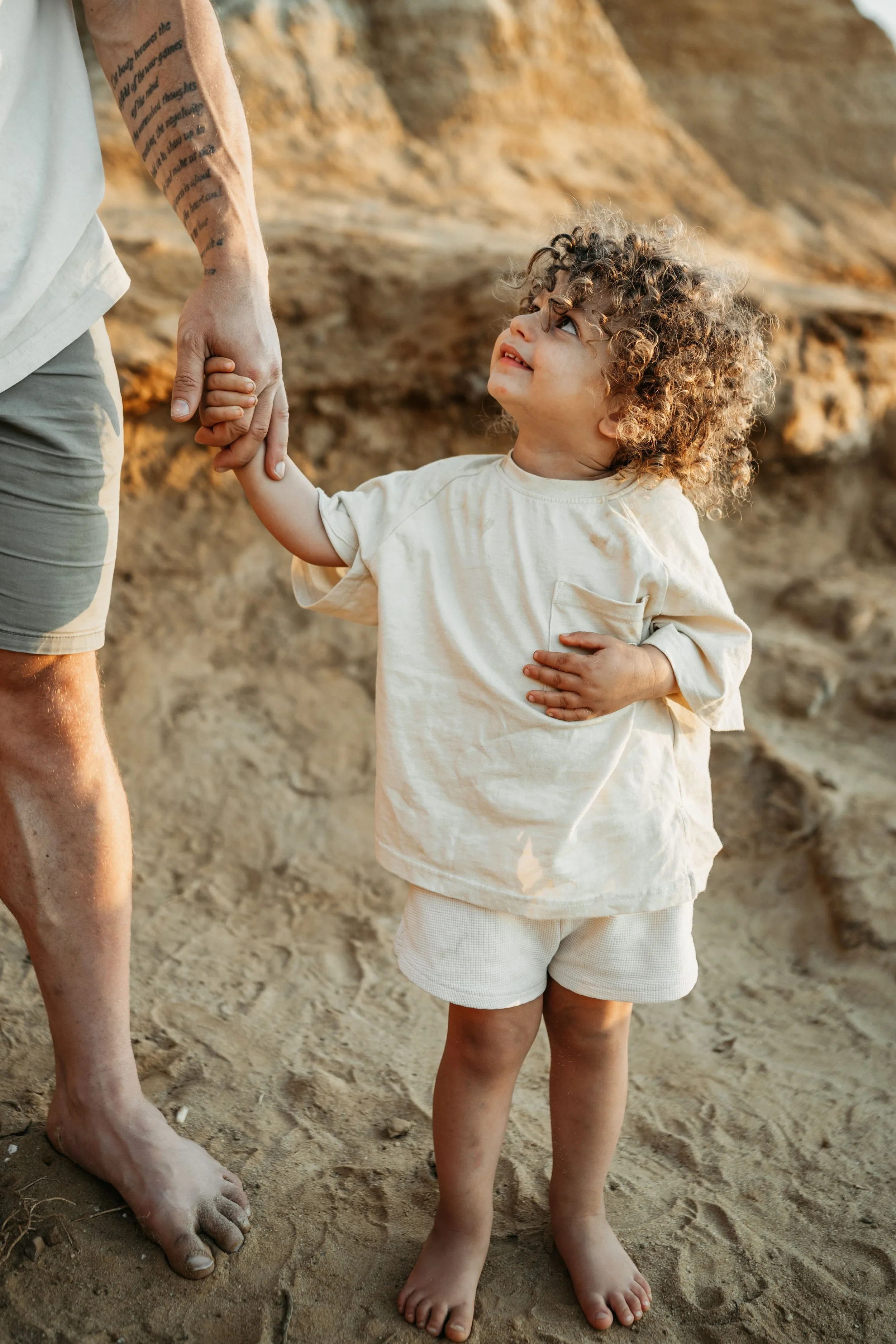 A little boy holding his Dad's hand looking up at his father