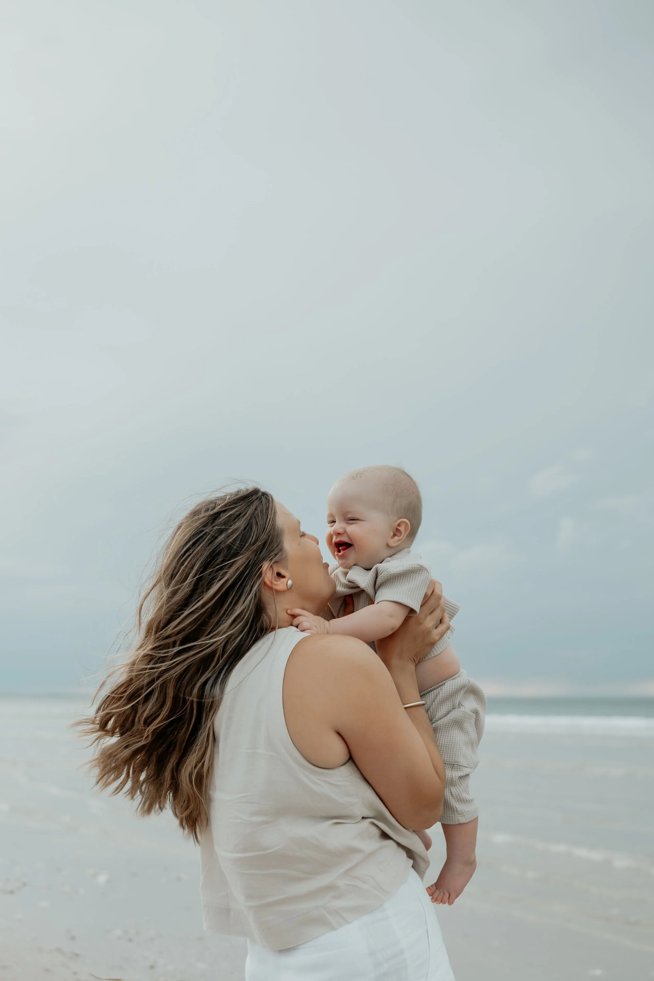 Mum and son playing on the beach. Son giggling and happy.