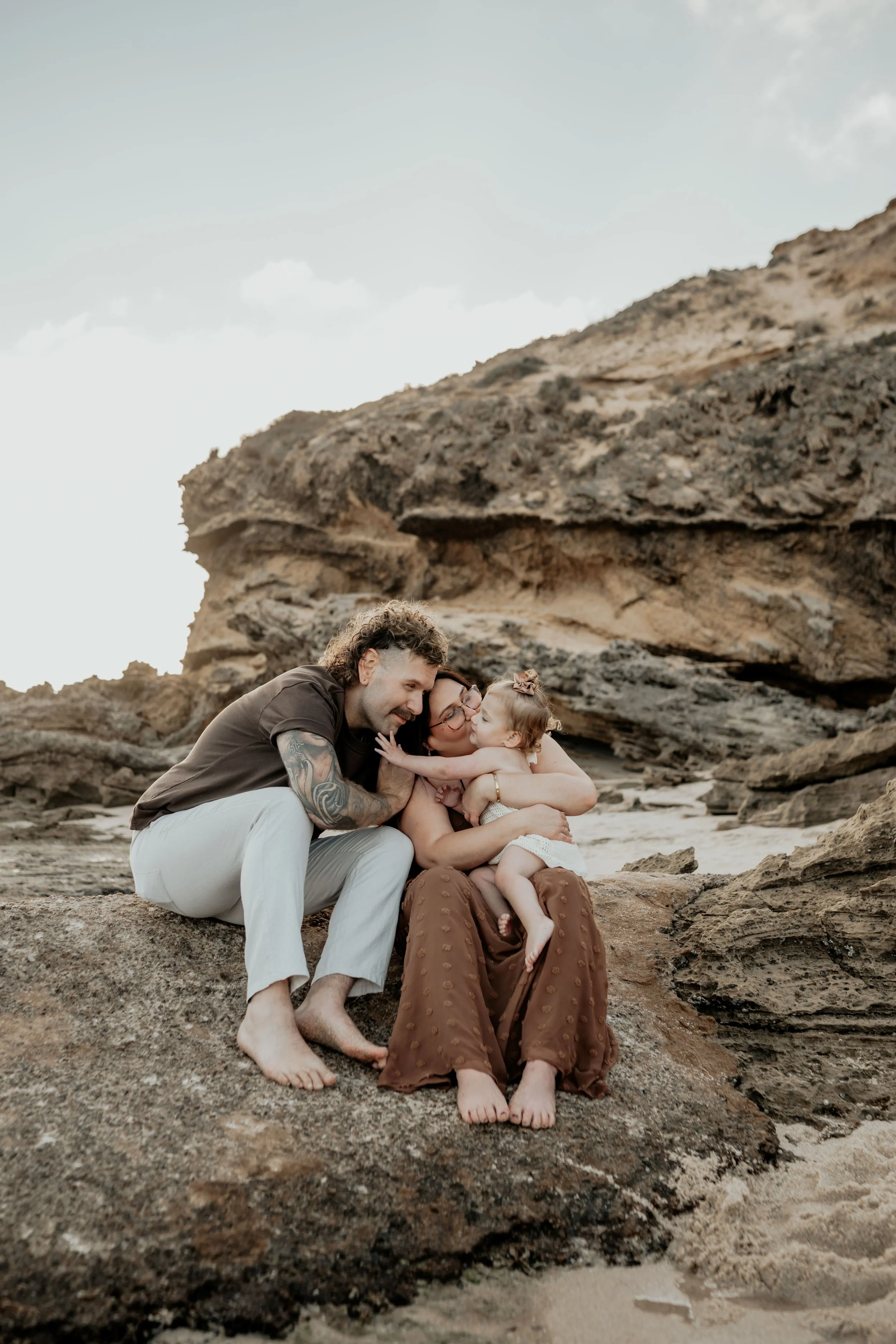 A mother and father sitting and playing with their daughter
