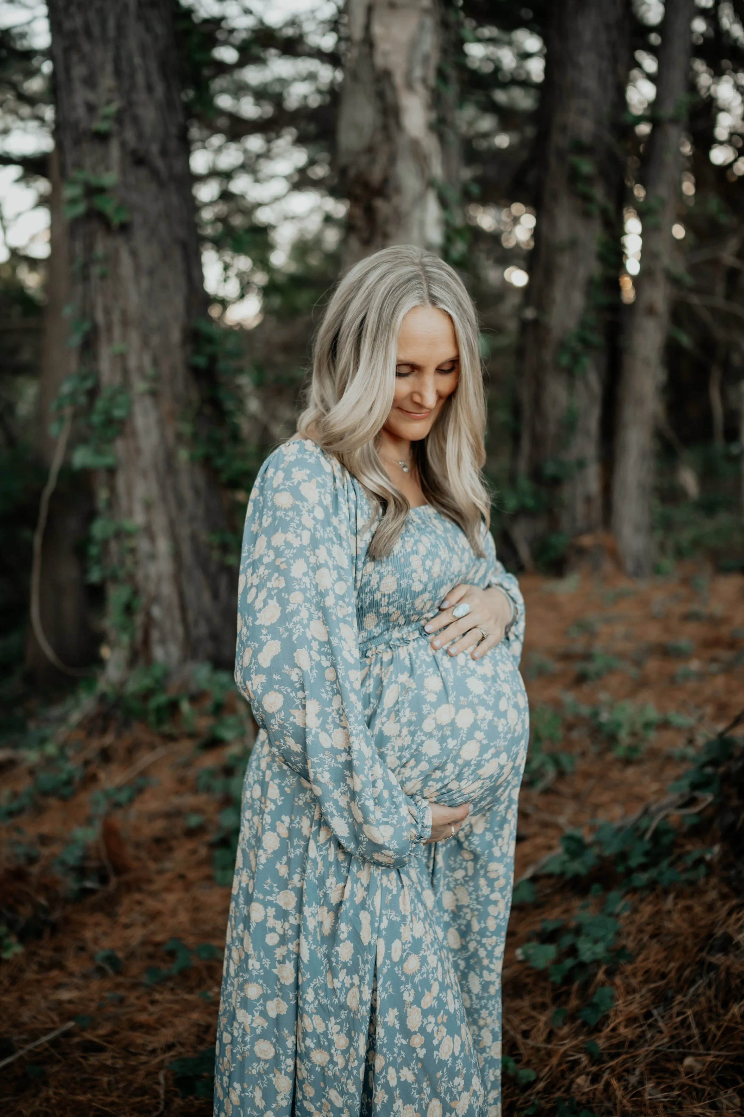 A pregnant mothers holds her belly smiling in the forest on the Mornington Peninsula