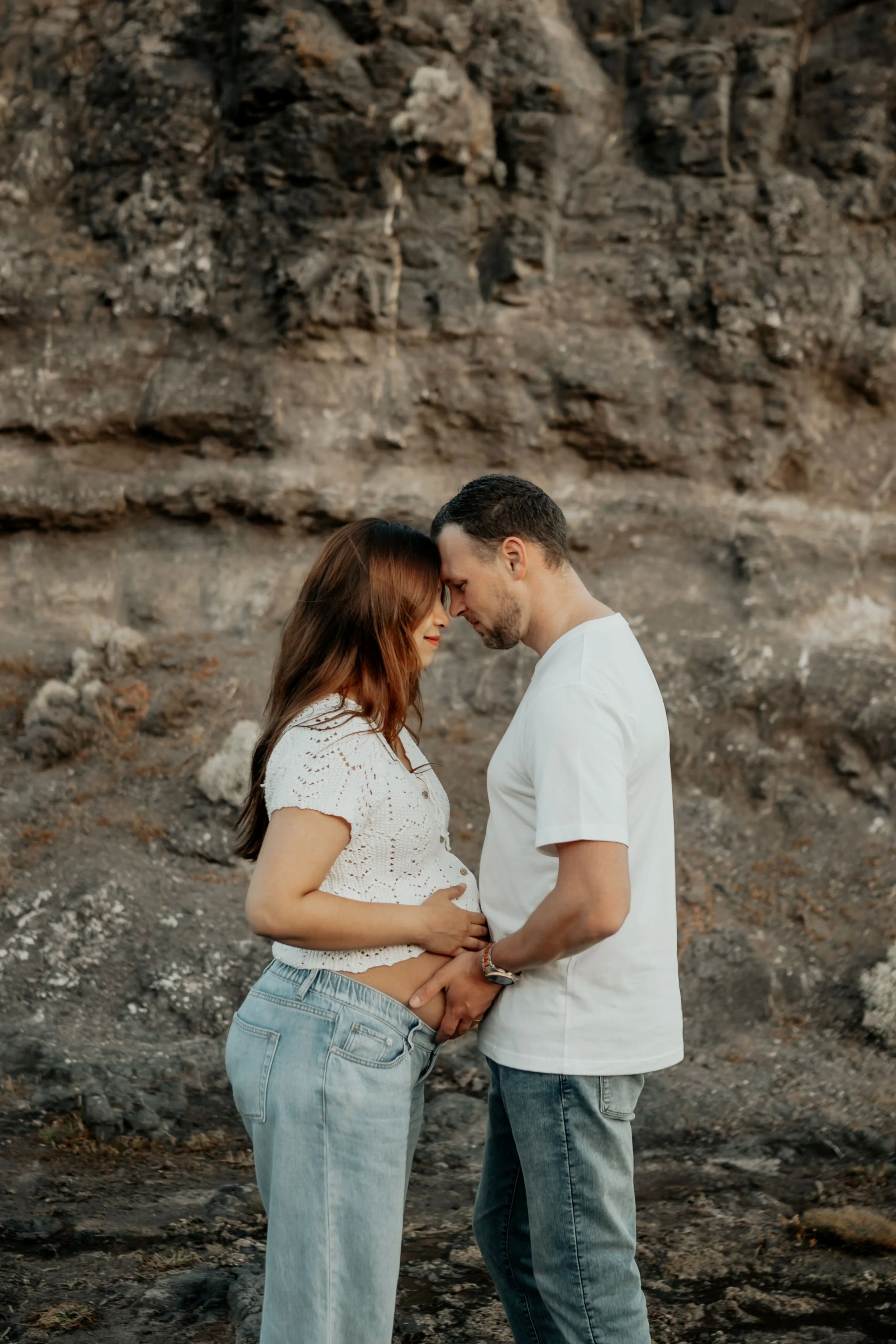 A pregnant couple embrace each other with their foreheads together