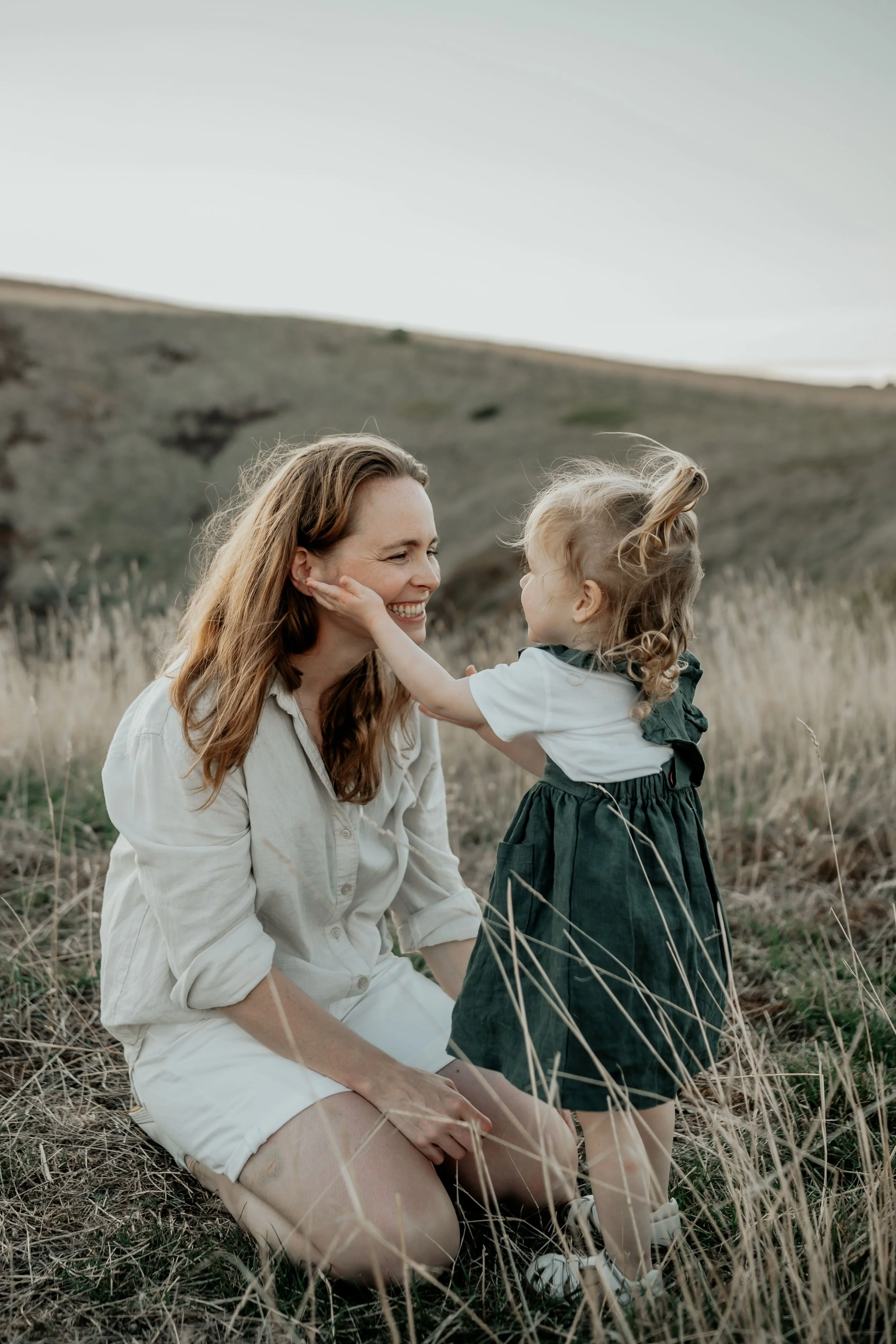 A little girl holds her mothers face