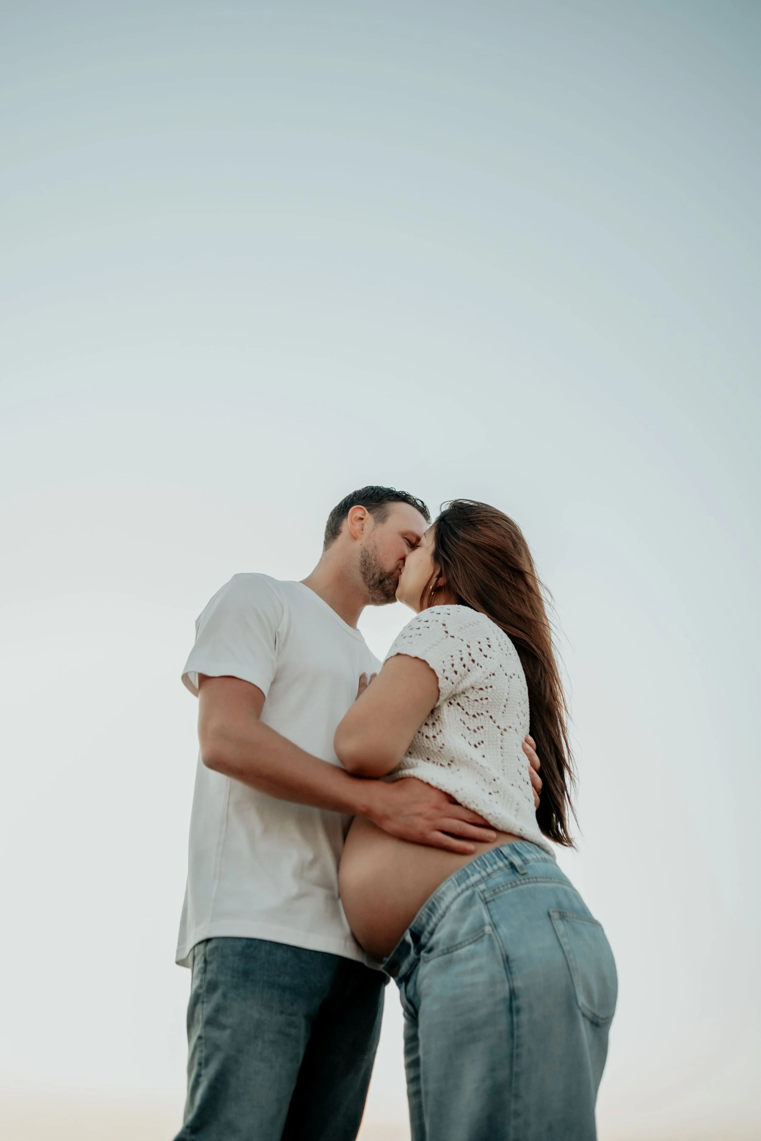 A pregnant couple kiss 