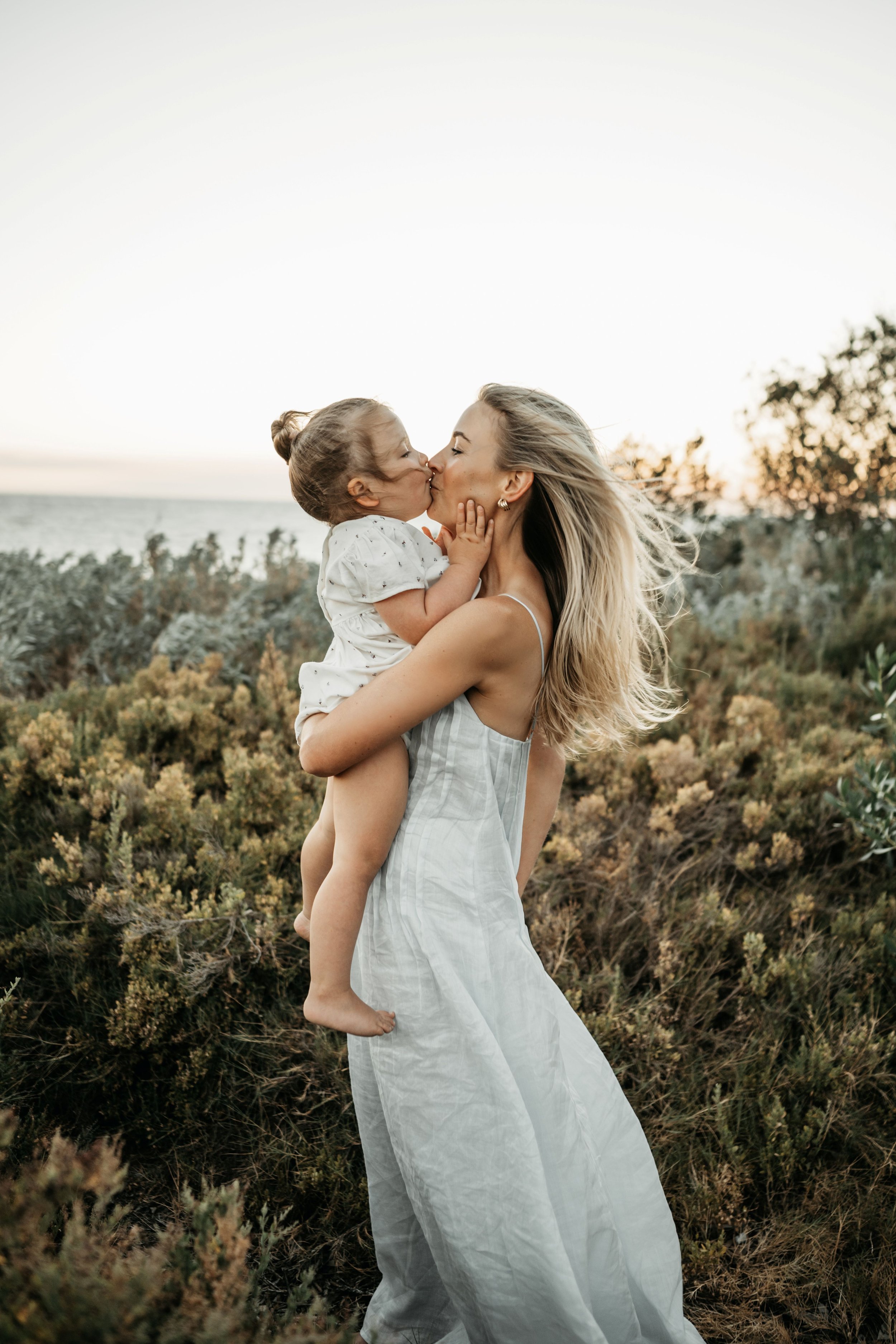 A mother and daughter standing together kissing each other