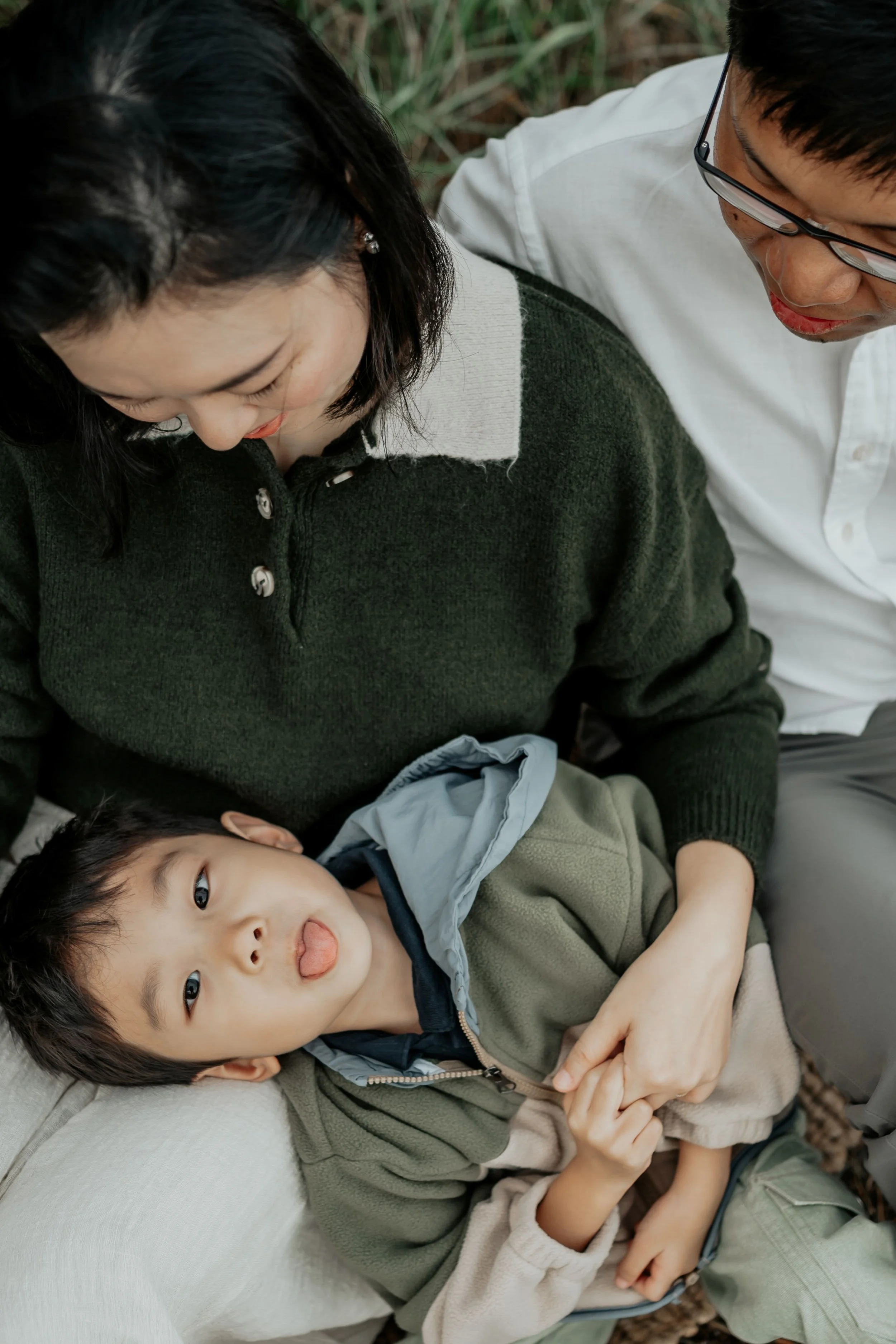 A little boy pokes his tongue out while his parents laugh