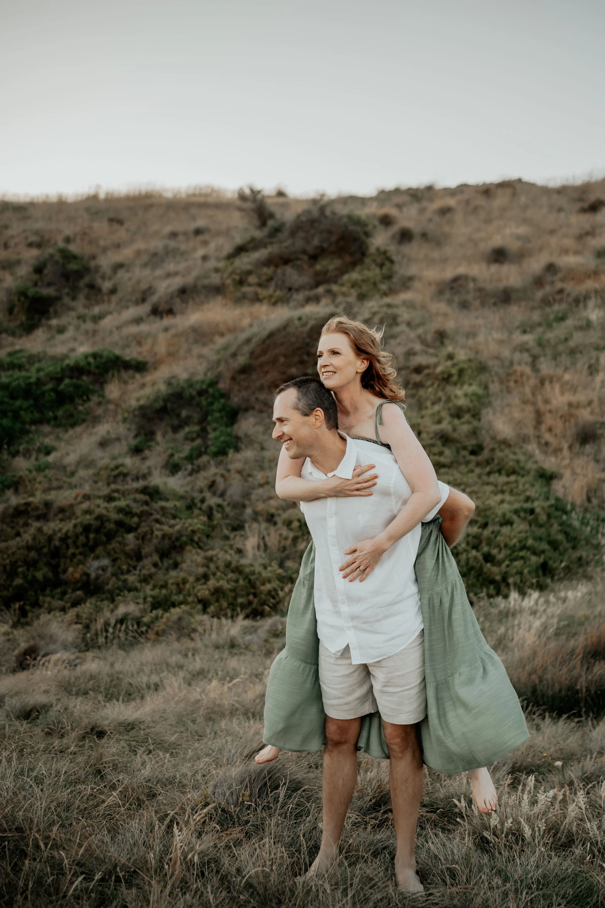 Husband piggy back his wife watching the wild ocean waves