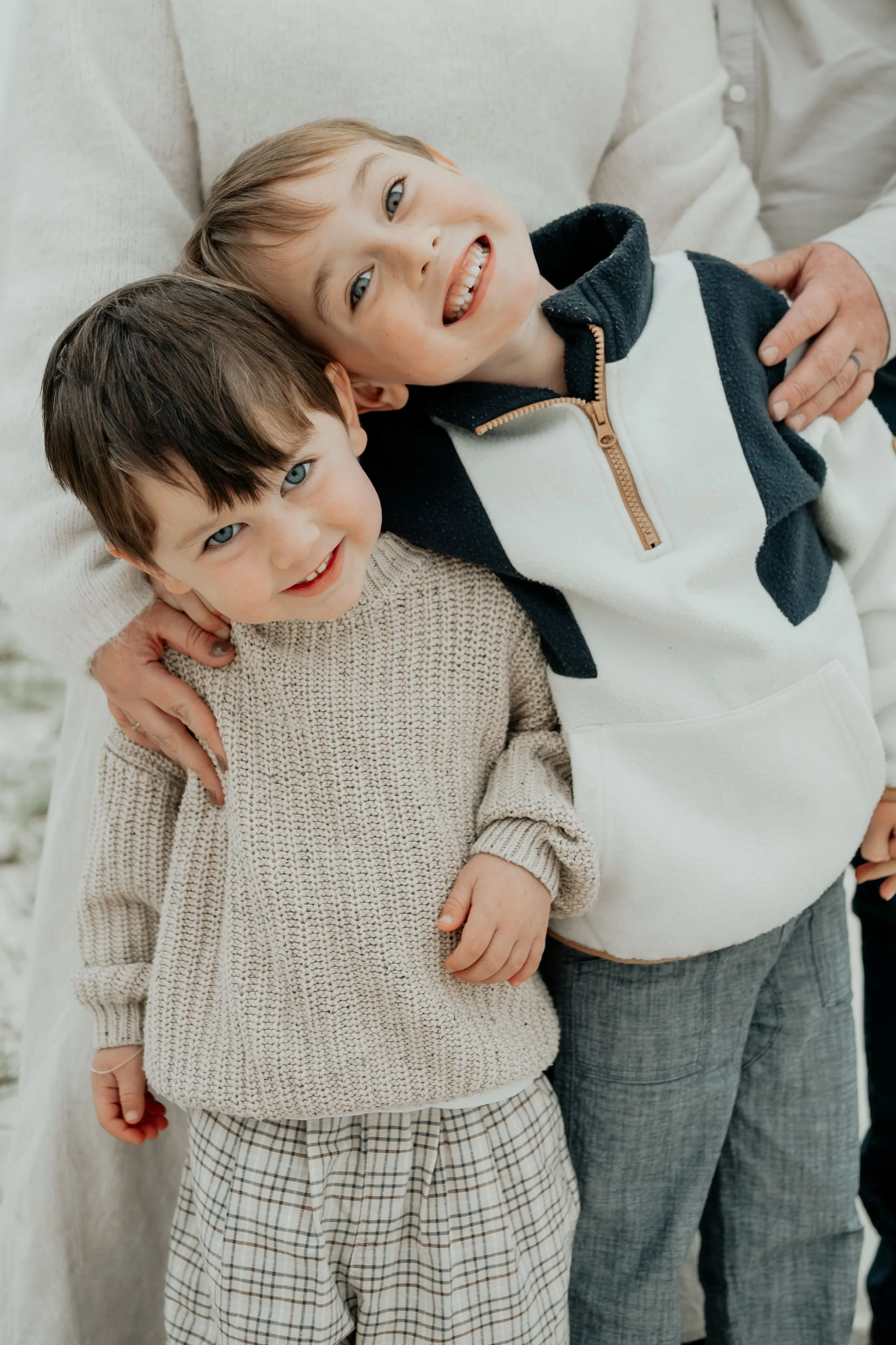 Brothers cuddle on the beach with big smiles during a family photo session on the Mornington Peninsula