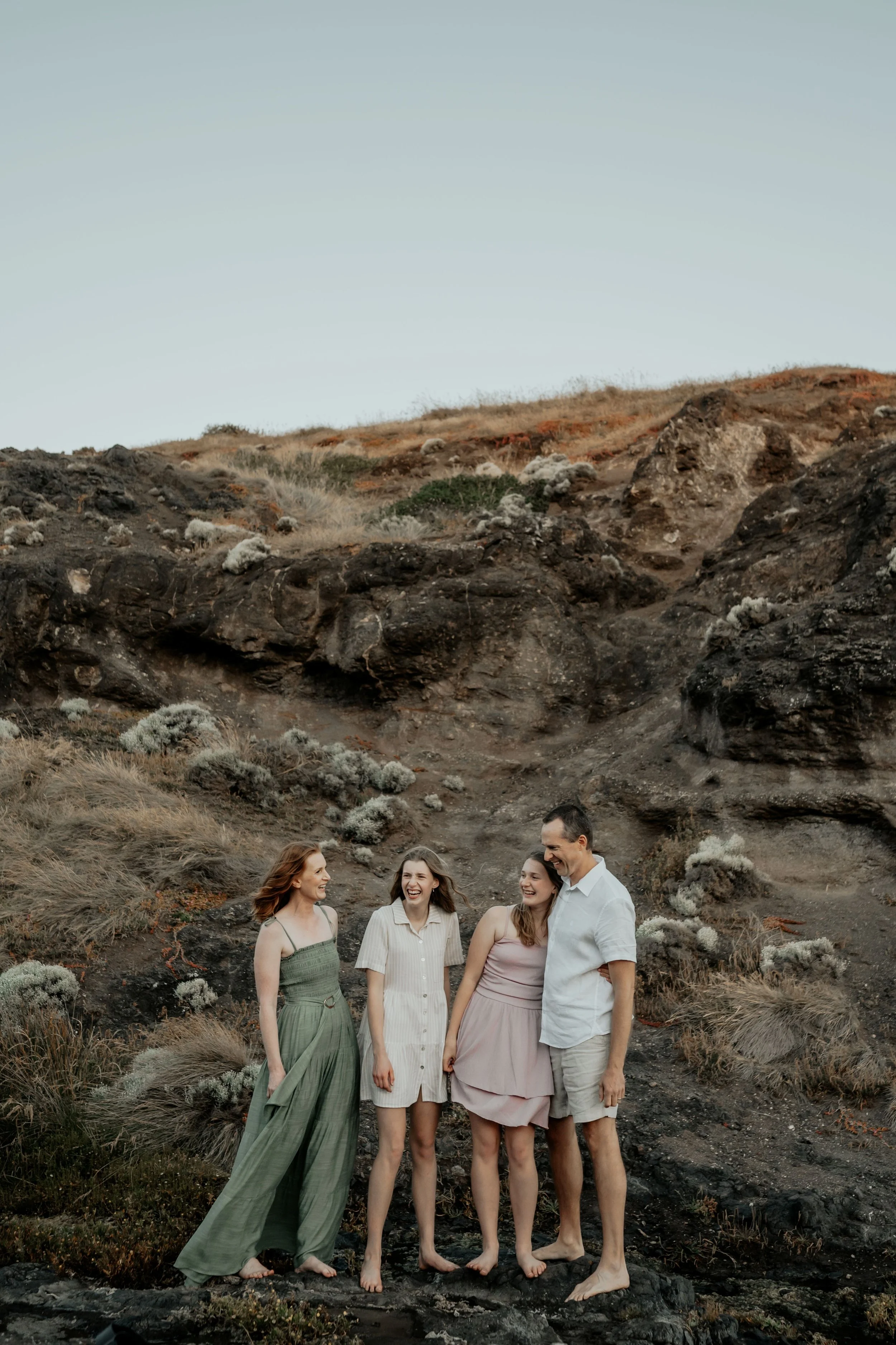 A family cuddle chat and laugh with a rock face backdrop