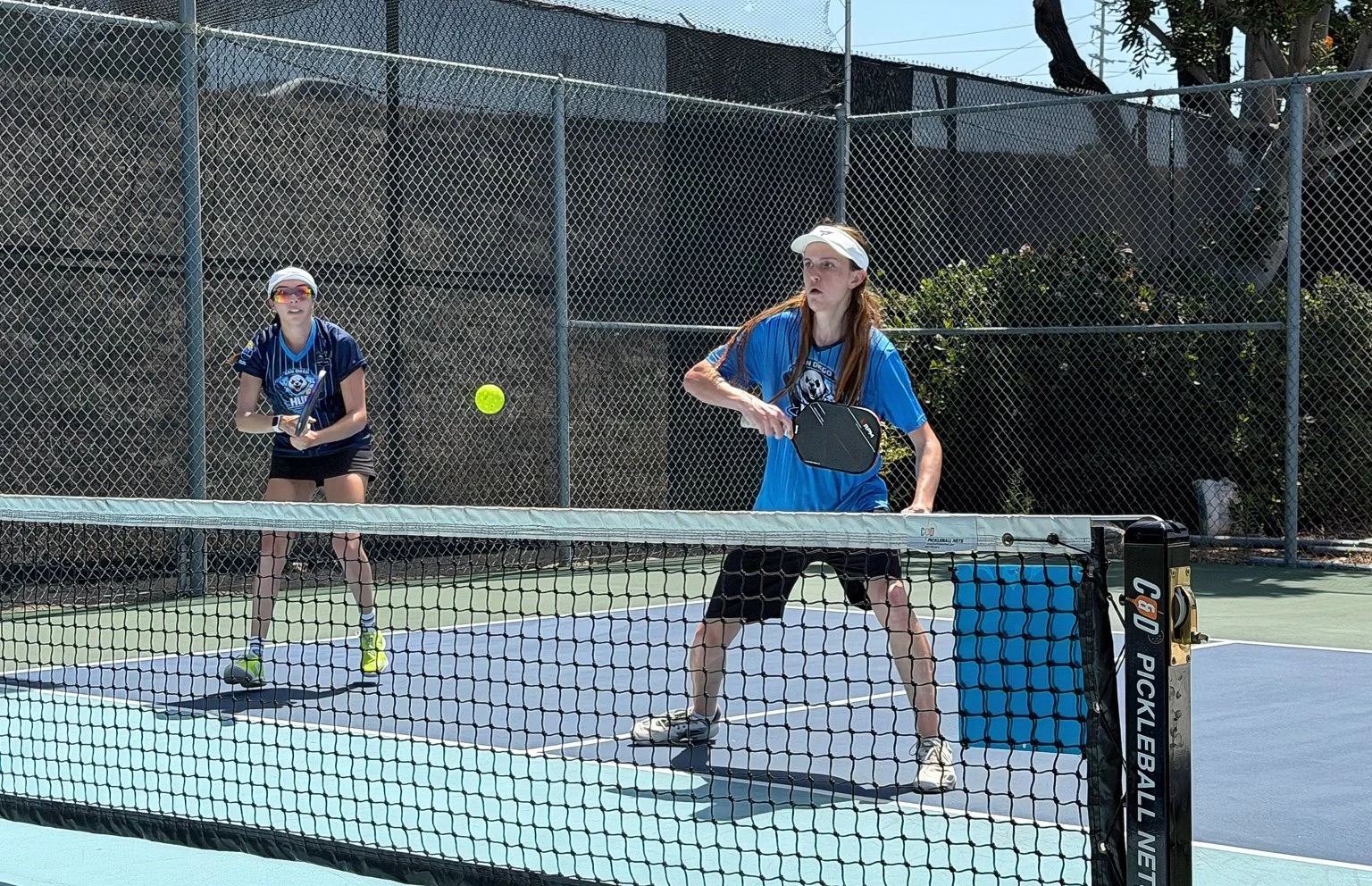 Owen and Elitza playing doubles on an outdoor pickleball court.