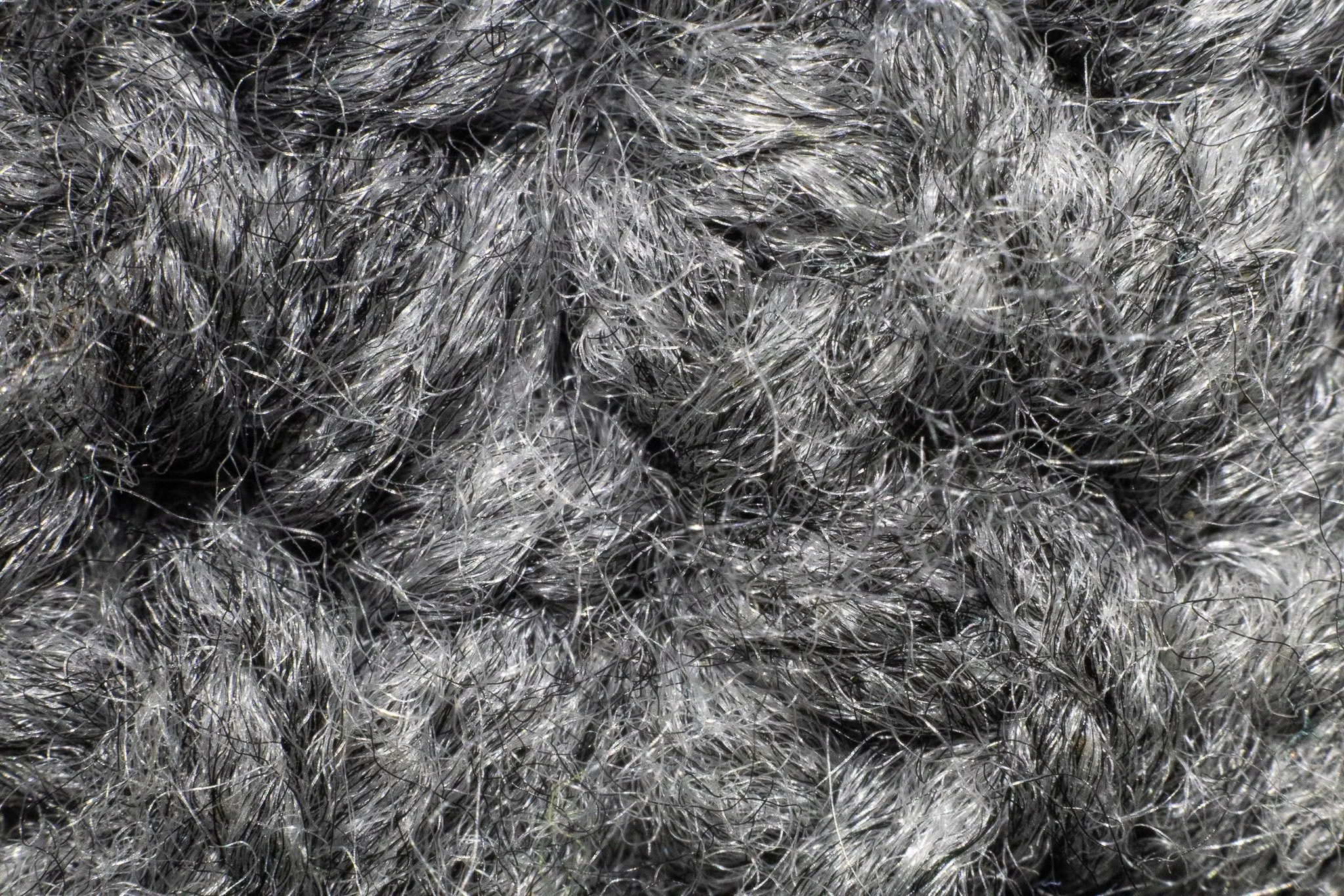 Close-up view of a tangled, dark gray and silverish synthetic fiber material.