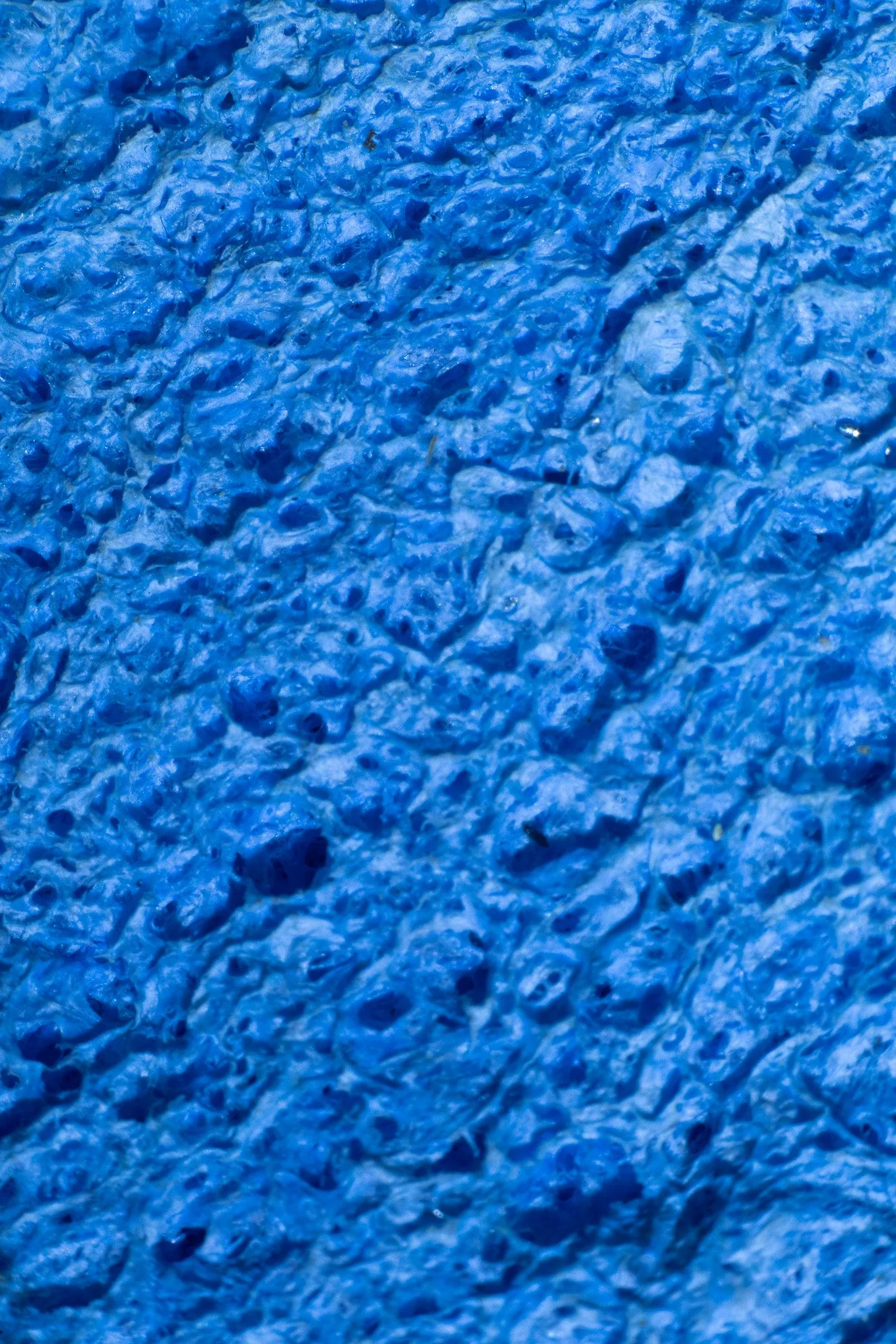 Close-up of a textured blue surface, which appears to be a painted or coated material with a rough, uneven texture.