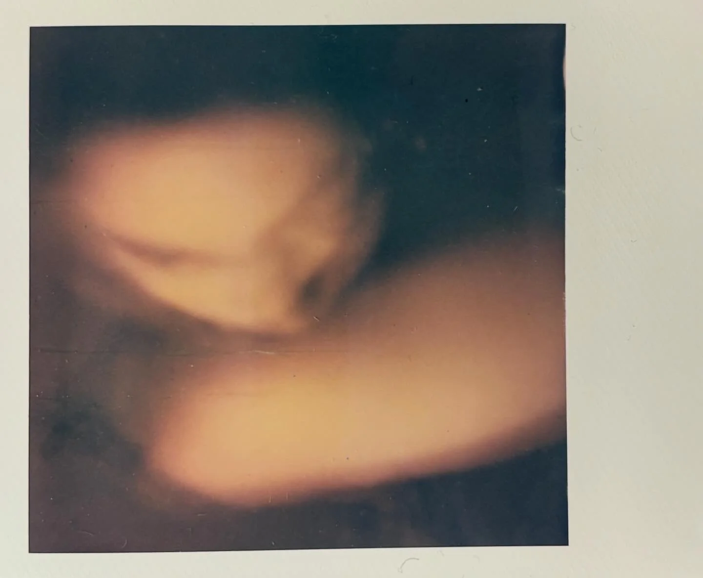 Abstract close-up photograph of a hand resting on a surface, with a soft focus and warm tones.