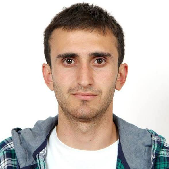 Man with short hair wearing a plaid shirt and gray hoodie.