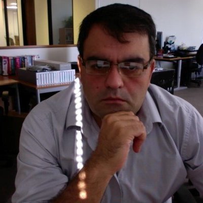 Man sitting in office, wearing glasses, with hand on chin