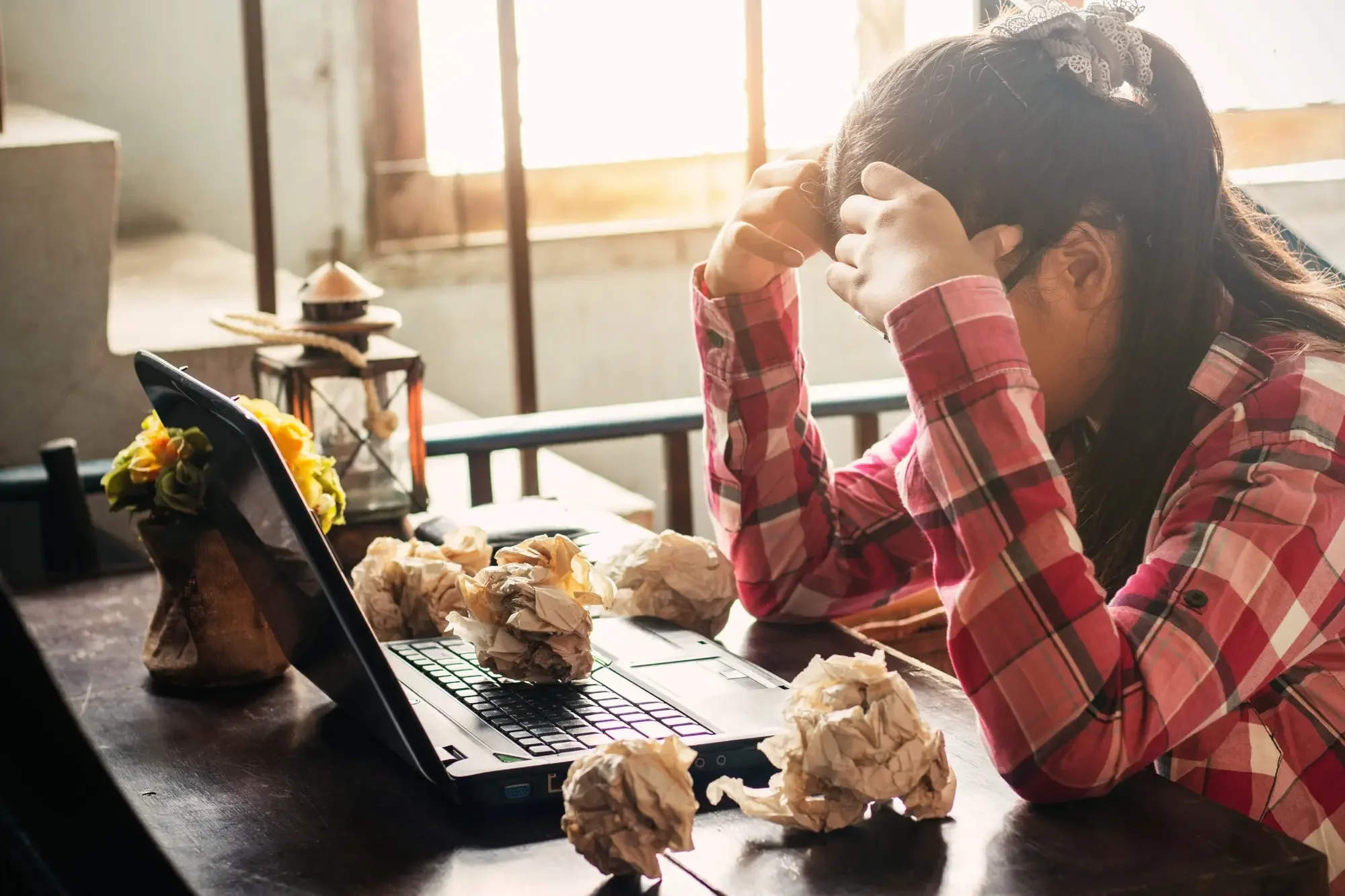Woman sat at table stressed looking at her computer