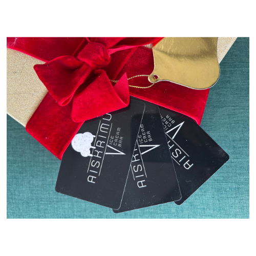 Three Aishriel ice cream bar gift cards with a black background, attached to a Christmas gift wrapped in gold and red paper with a red velvet bow.