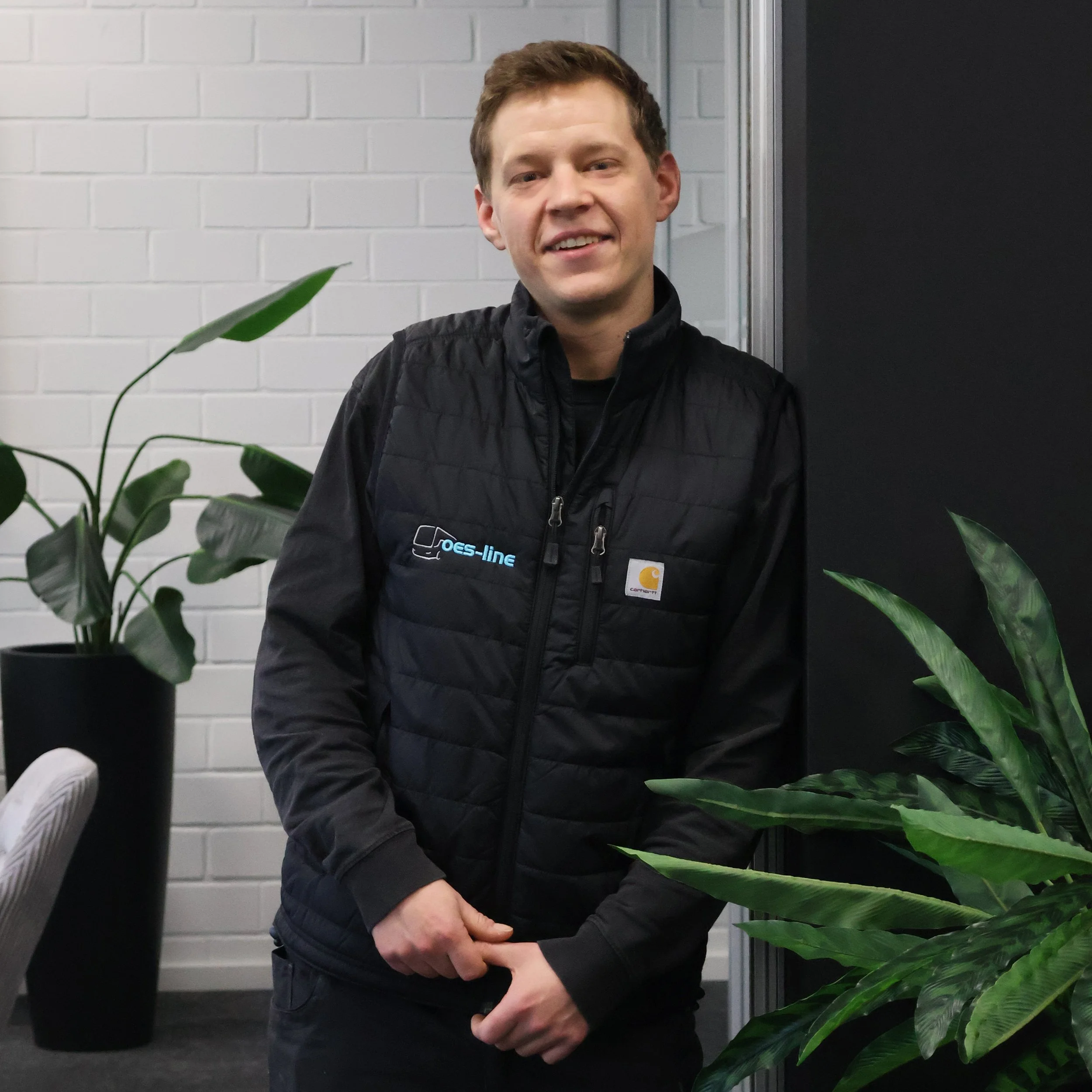 Mann in schwarzem T-Shirt mit Elektrowerkzeug in Werkstatt