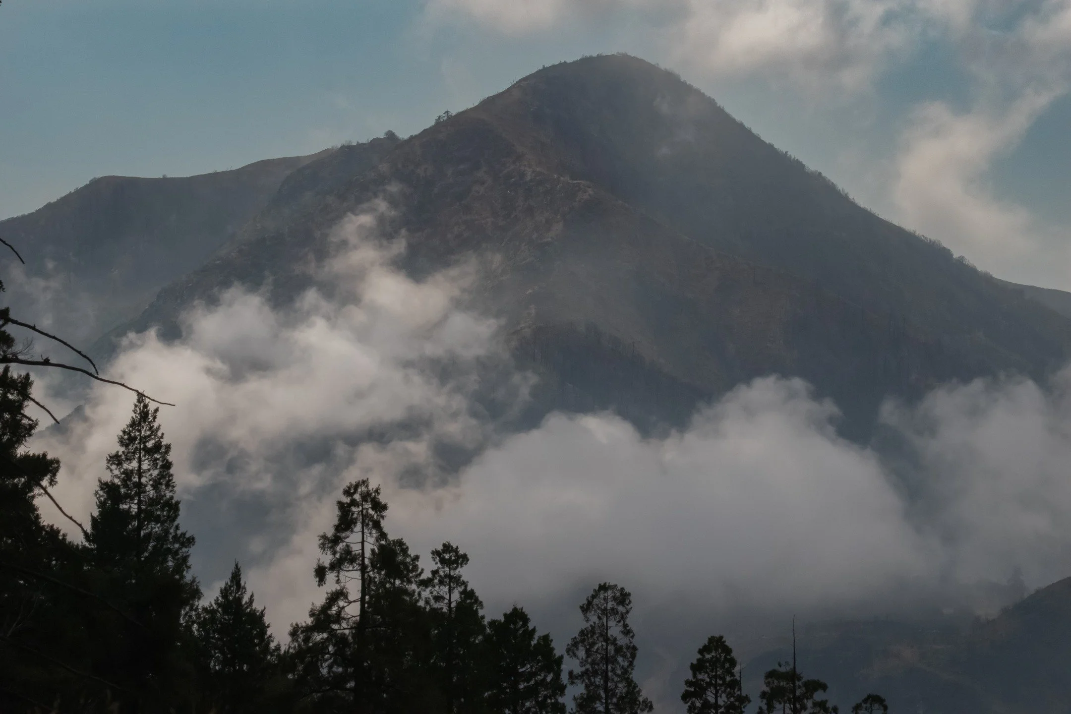 This photograph captures the majesty of a mountain partially hidden by drifting clouds, embodying mystery, power, and peace. It reflects endurance and grounding, inviting viewers to pause and draw strength from nature’s timeless presence. A per