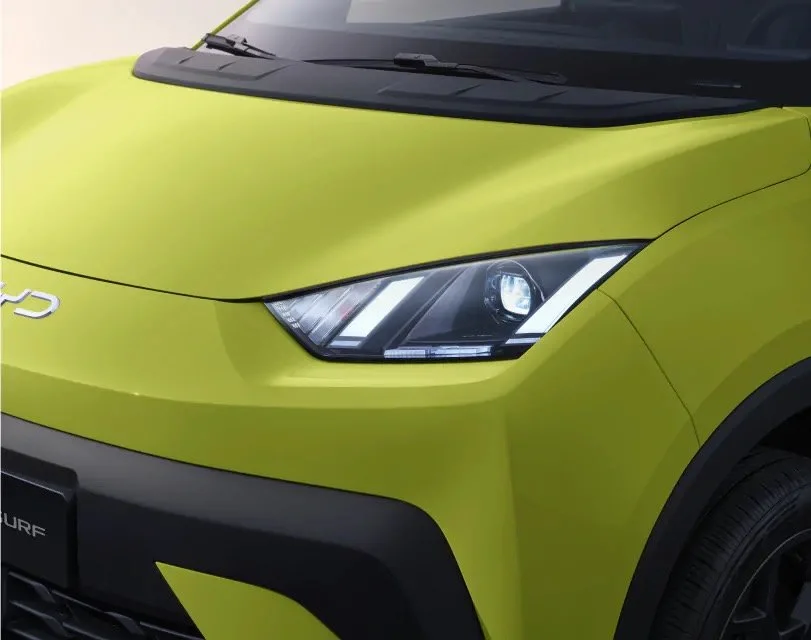 Zbliżenie na przedni reflektor LED o ostrym, geometrycznym kształcie w elektrycznym modelu BYD Dolphin Mini (Seagull) w charakterystycznym limonkowym lakierze.