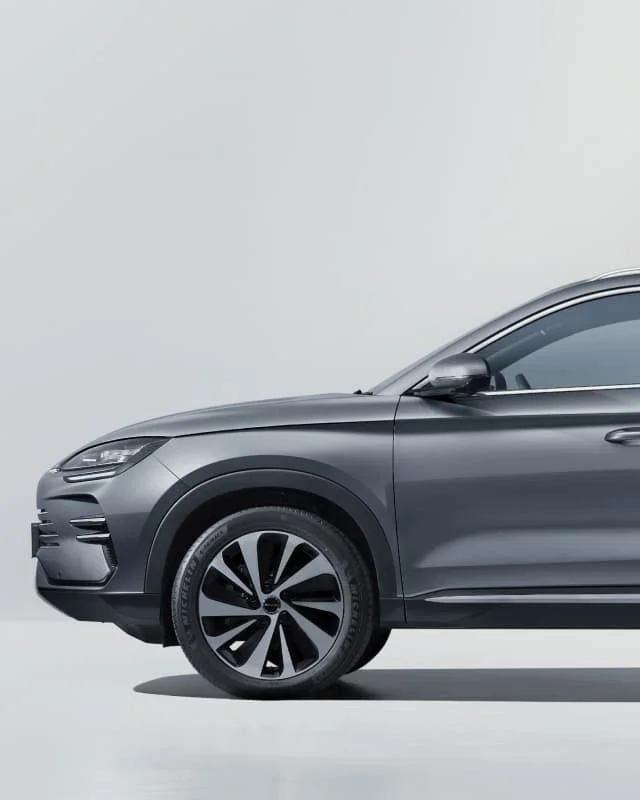 Przednia część nadwozia i profil eleganckiego, szarego SUV-a BYD Seal U DM-i, prezentujący dynamiczny reflektor, dopracowane przetłoczenia boku oraz dwukolorową felgę aluminiową na jasnym tle.