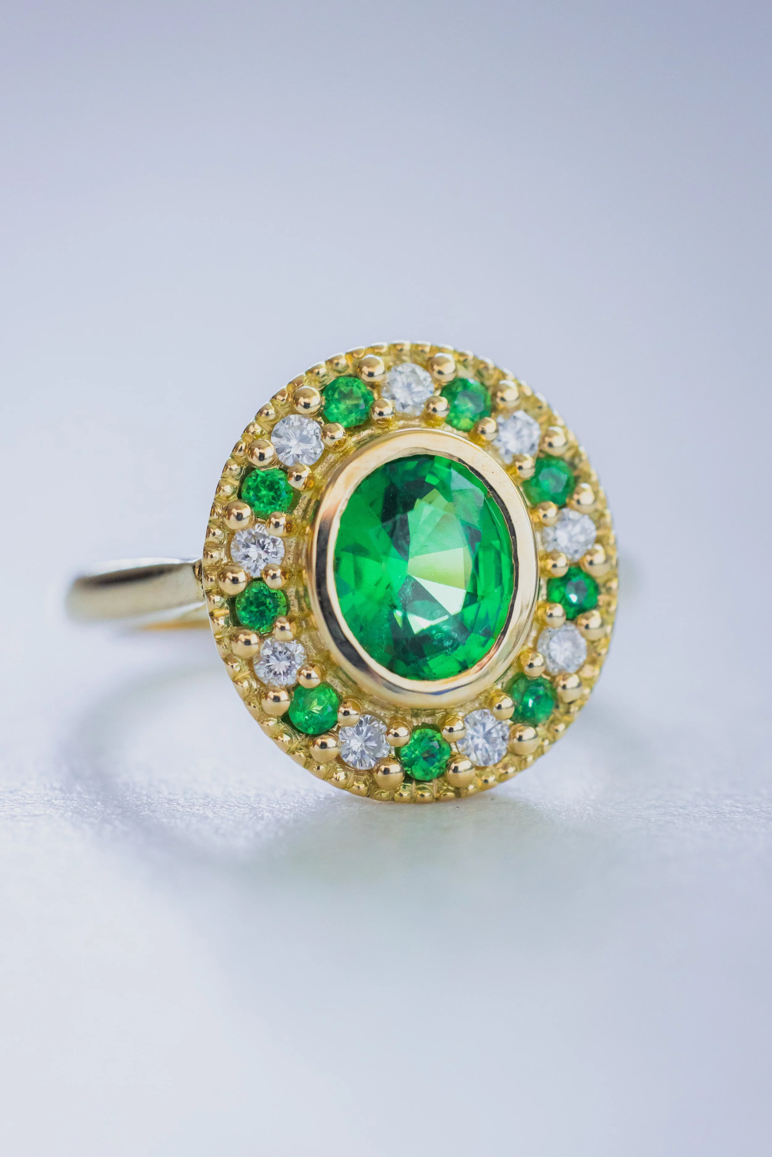 Bague style art déco en or ornée d'une tsavorite centrale ovale entourée de petits diamants et de tsavorites