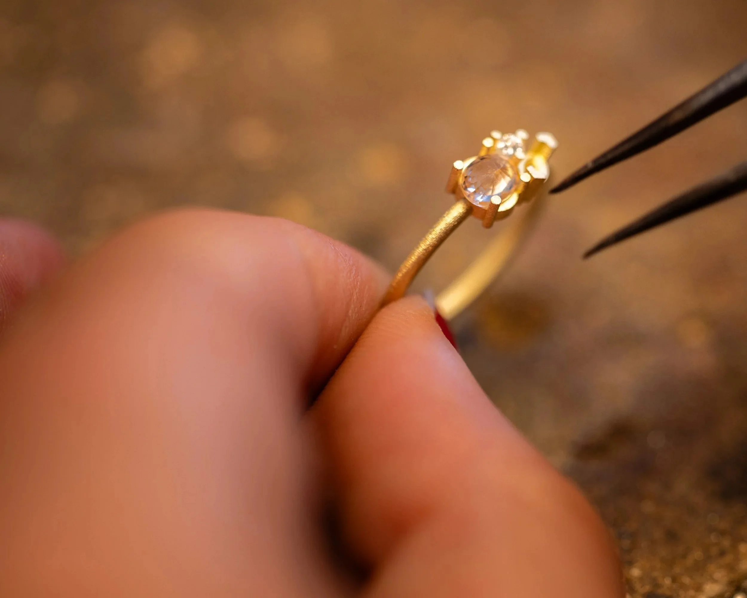 Artisan joaillier à Montpellier qui travaille dans son atelier tenant une bague en or avec un saphir jaune