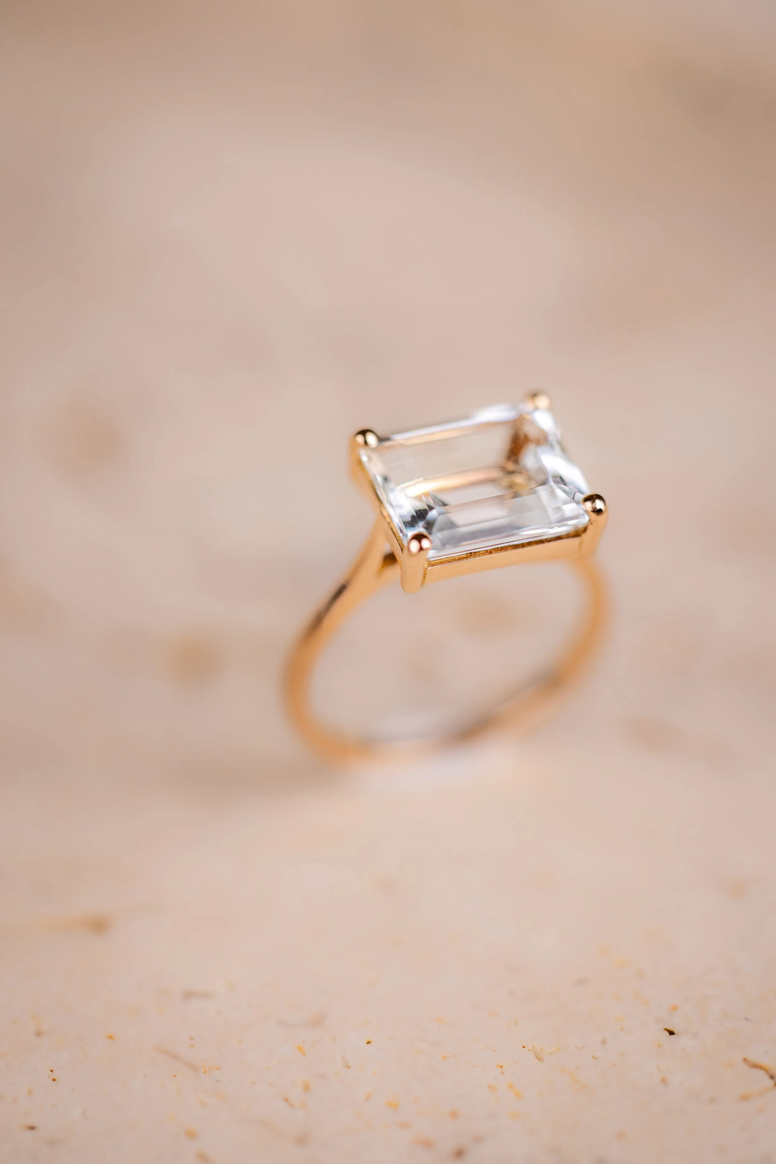 Bague avec une aigue marine rectangulaire claire sur un fond beige
