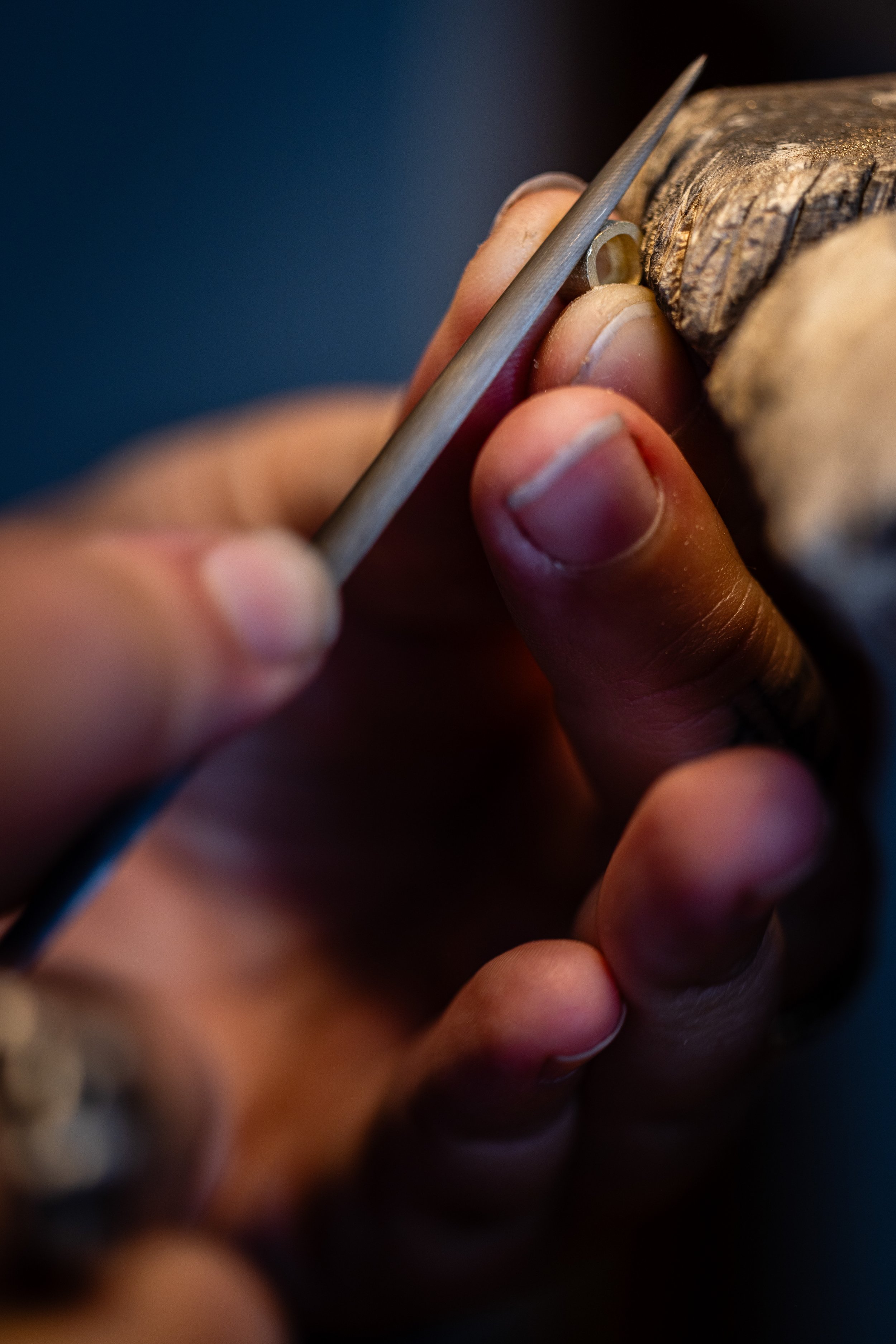 Artisan joaillier travaillant sur son établi en train de limer un pendentif en or