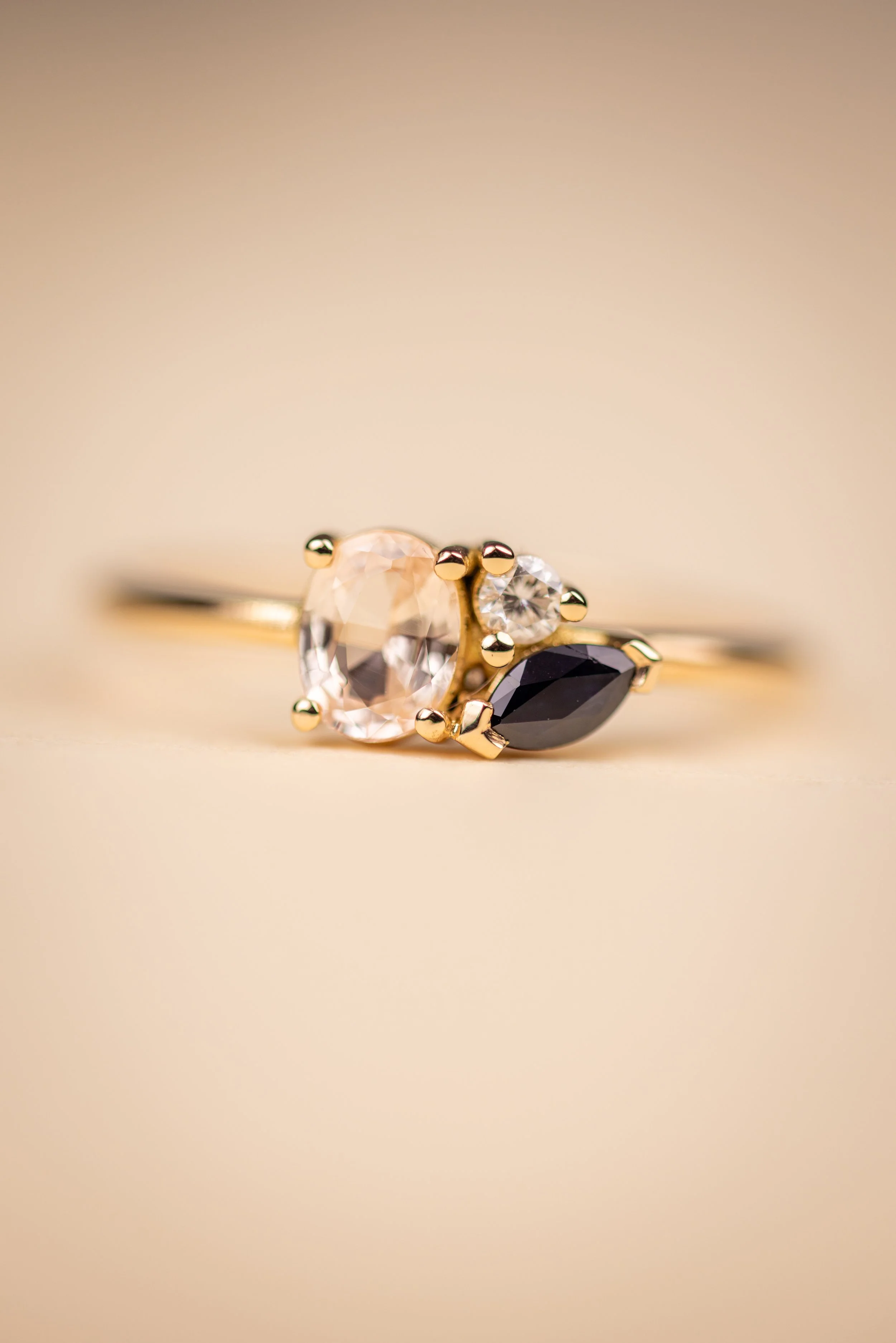 Bague après transformation en or avec trois pierres précieuses : un saphir pêche, un saphir bleu marquise, et un diamant en haut à droite.