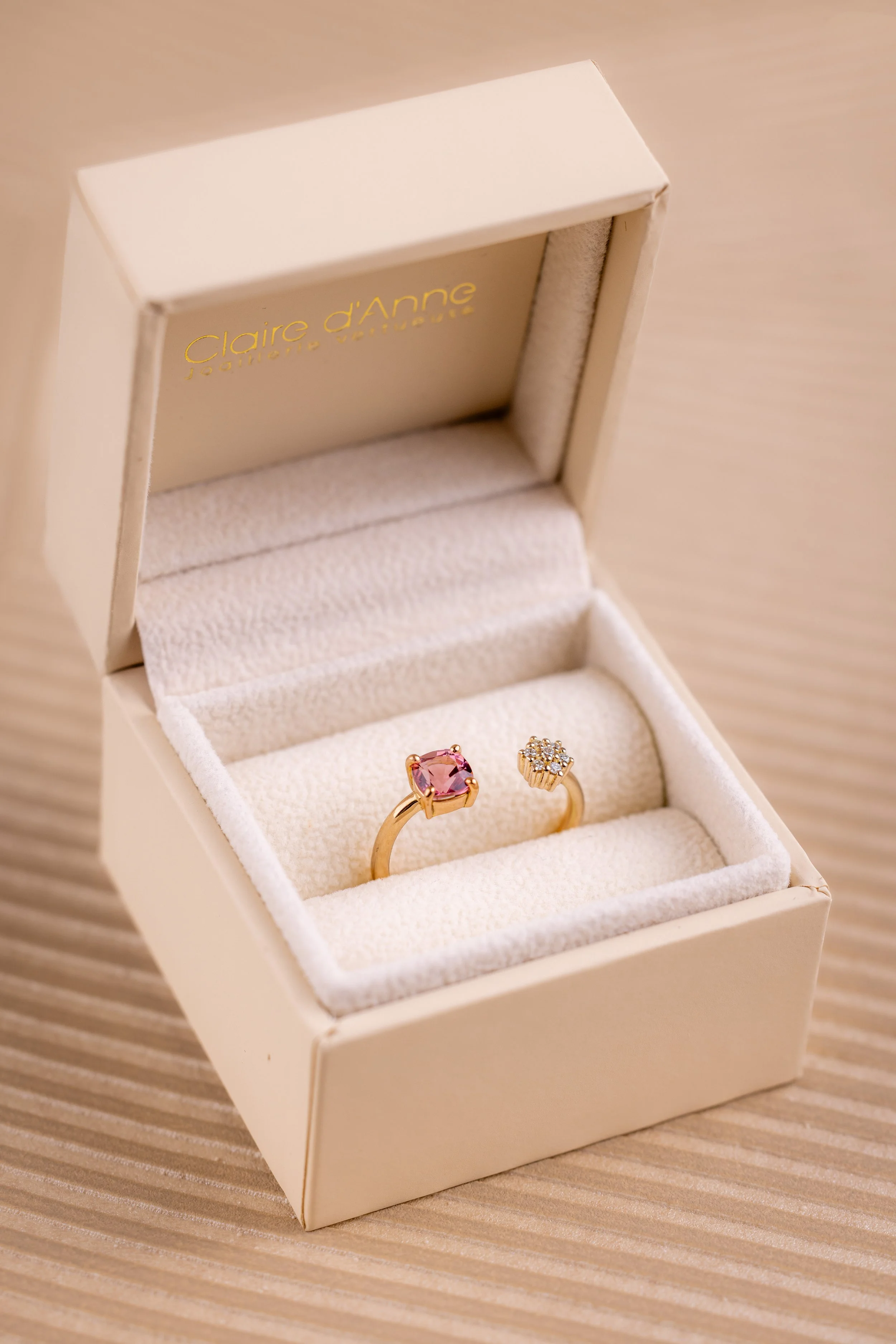 Bague de fiançailles en or rose dans un écrin beige, sertie d'une tourmaline rose taille coussin et d'une fleur en diamants