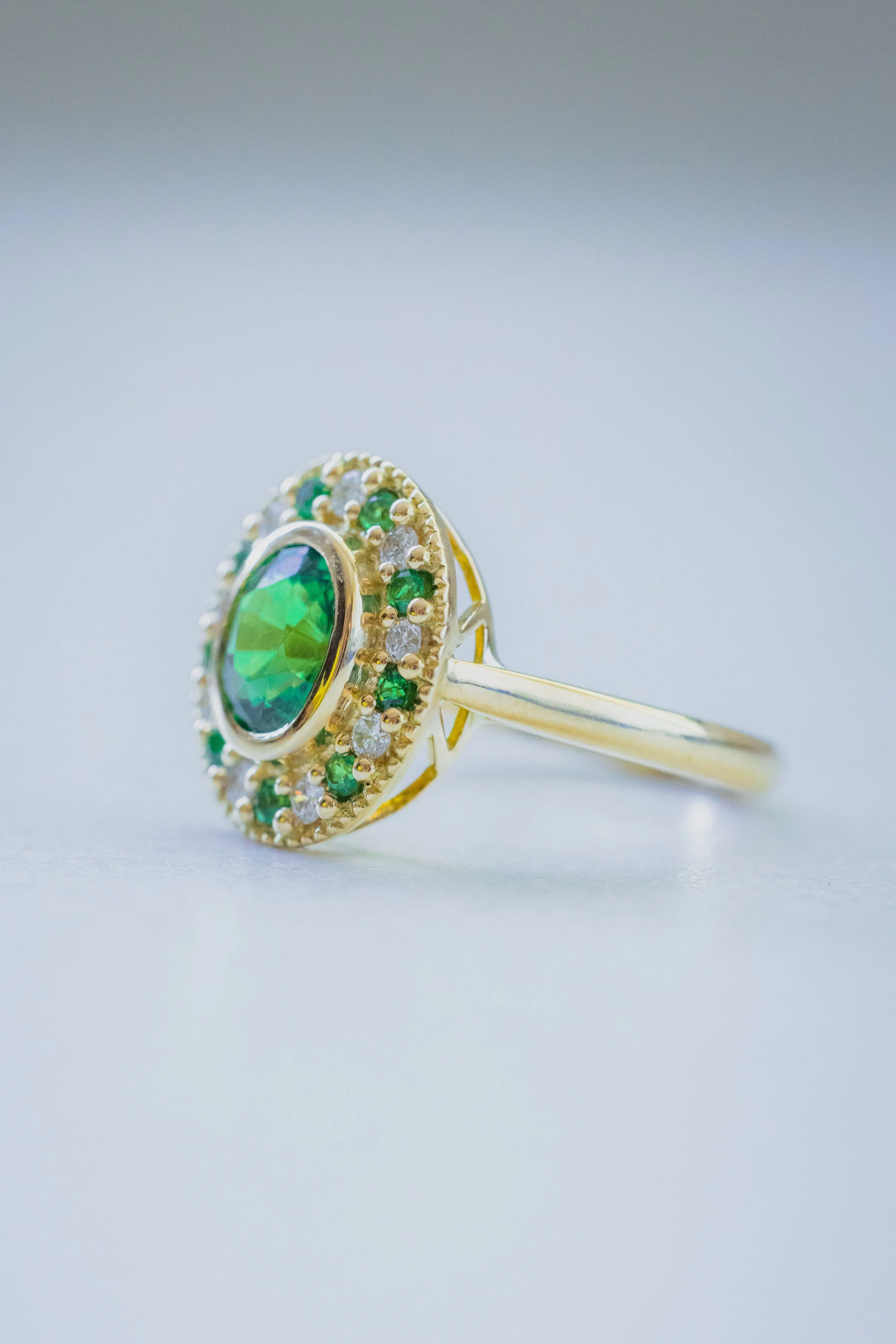 Bague en or jaune sertie d'une tsavorite ovale entourée de diamants et tsavorites ronds..