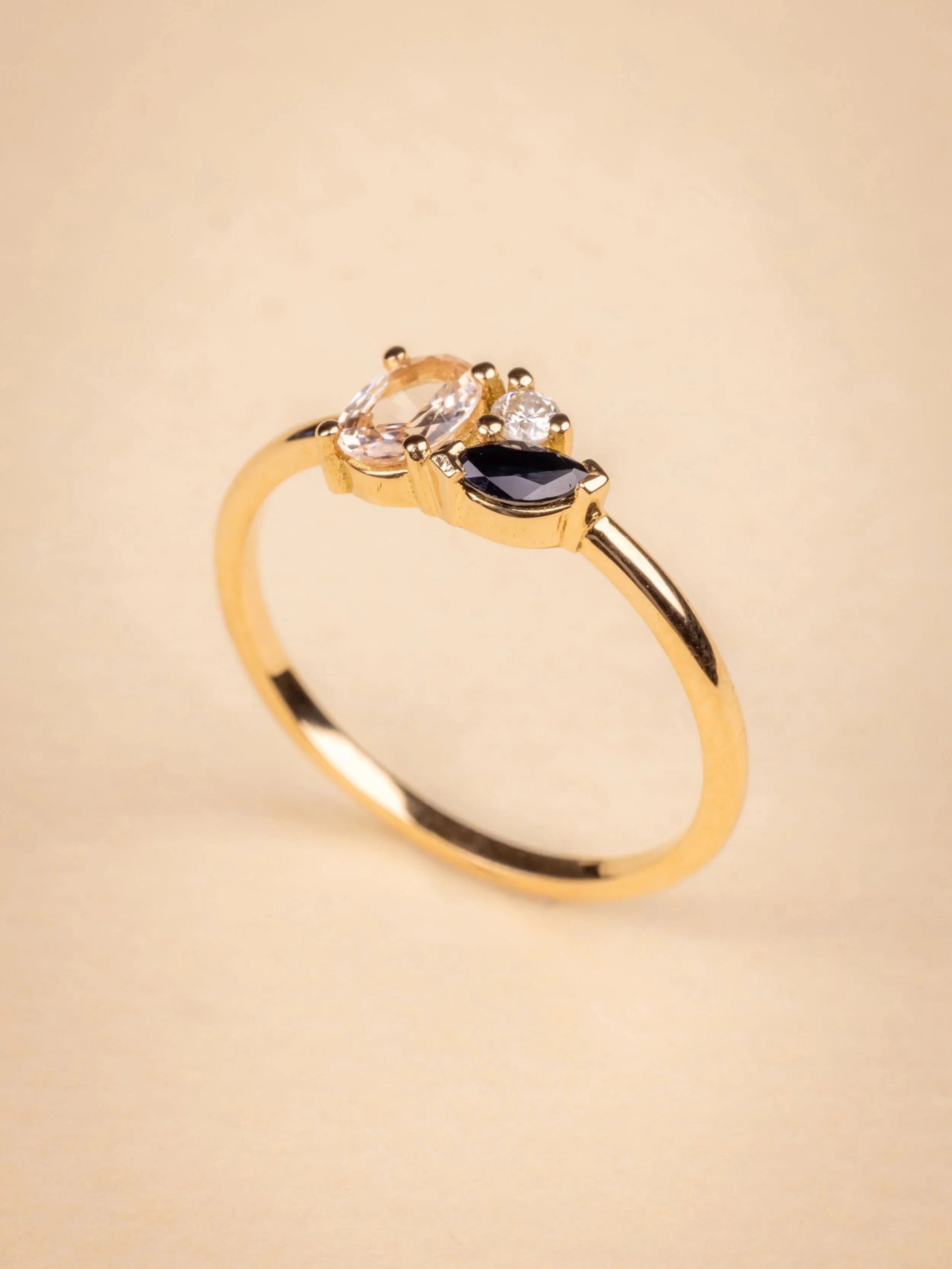 Bague en or jaune après transformation avec trois pierres précieuses de différentes couleurs et tailles.