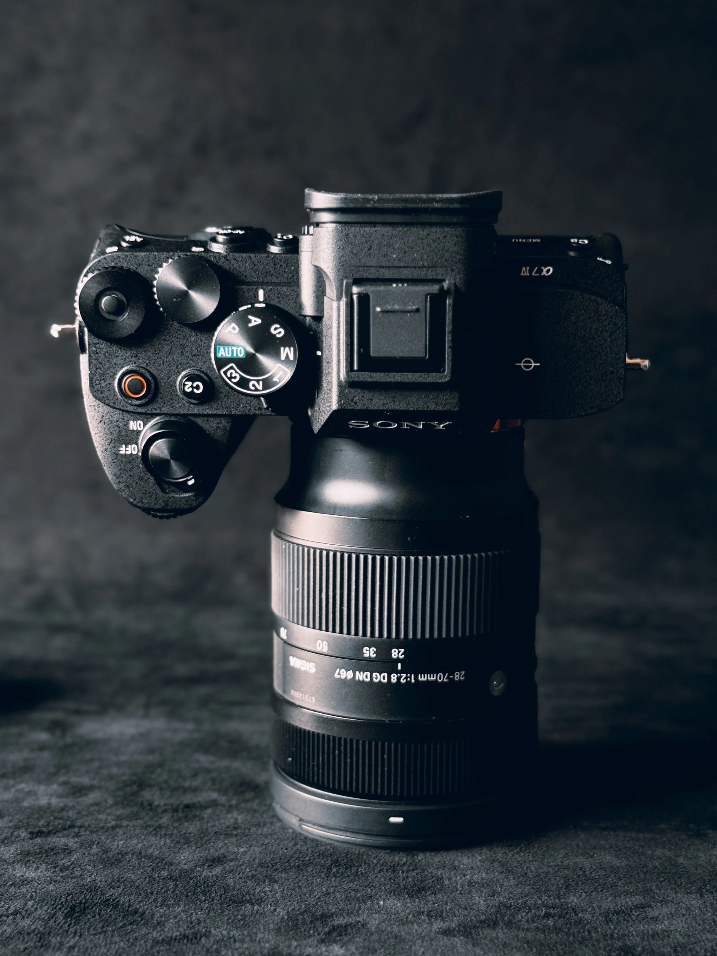 A black Sony mirrorless camera mounted on a camera lens against a dark background.