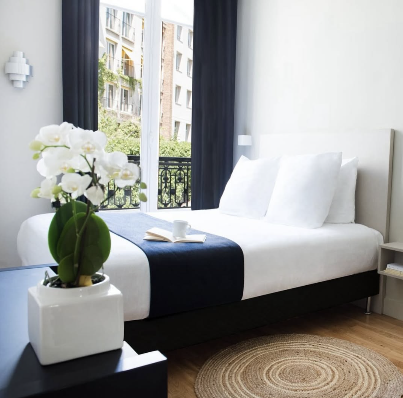 Chambre d'hôtel de l'hôtel helzear étoile dans les ton noir et blanc avec un joli parquet. Il y a également une belle orchidée en premier plan.
