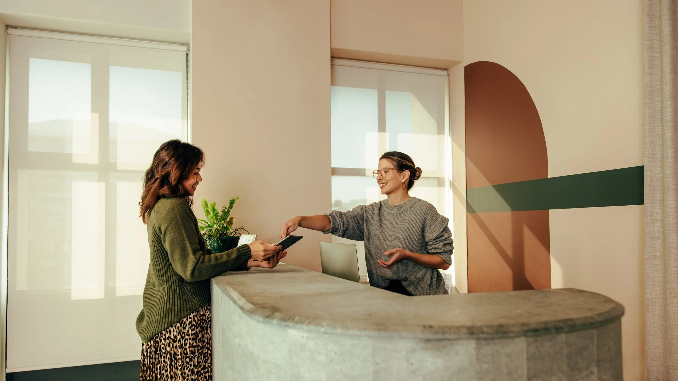 Deux femmes à la réception d'un hôtel. La réceptionniste donne les clés de la chambre à la cliente.