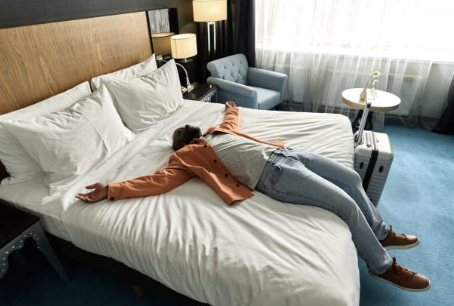 Homme heureux et allongé sur le lit de sa chambre d’hôtel.         