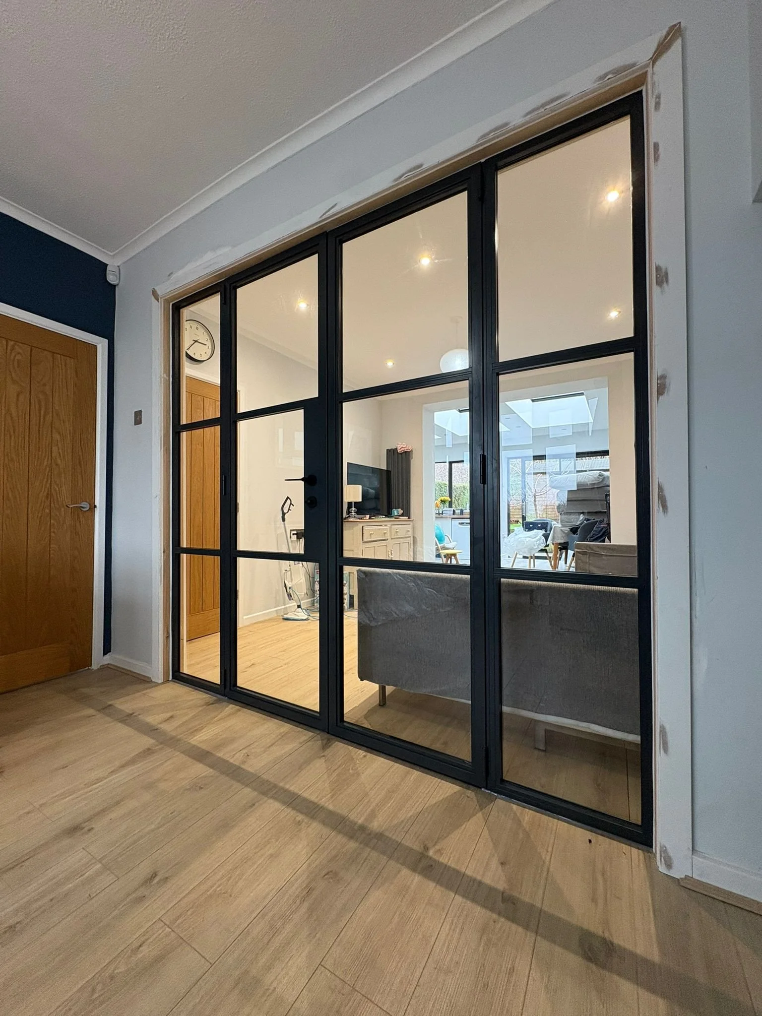 Interior view of a home with a black-framed glass partition door separating the living room from the hallway.
