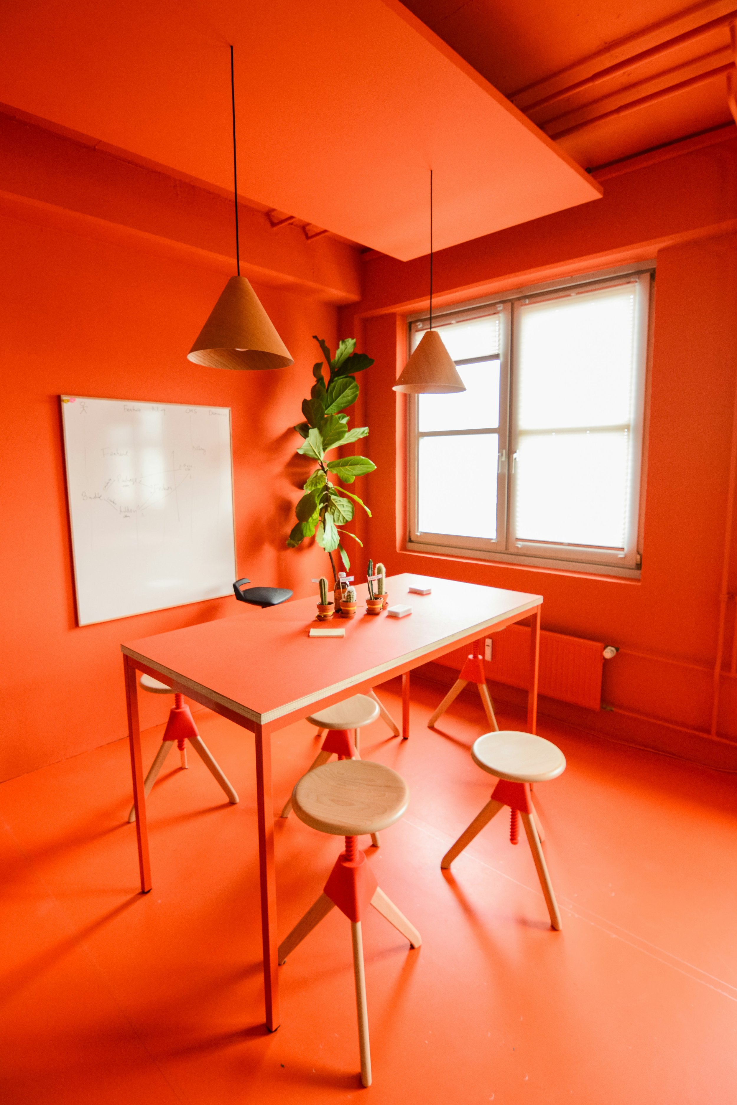 orange office with desk and chairs, whiteboard and a plant in the corner. A space for business owners and founders to focus and brainstorm.