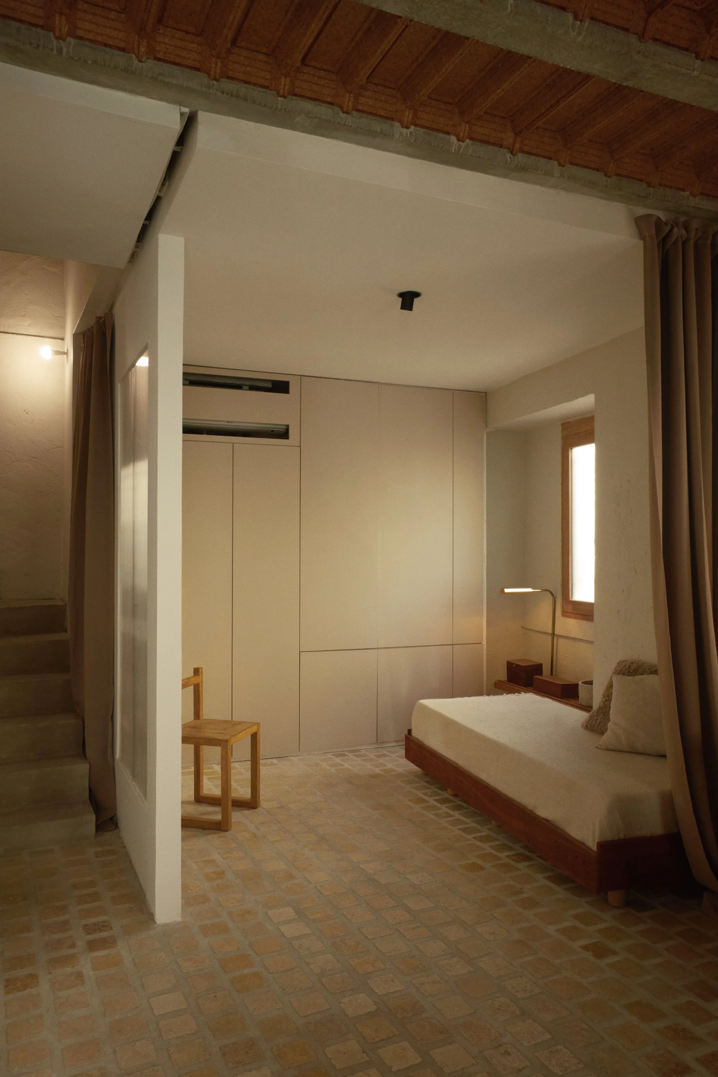 Chambre minimaliste dans une maison rénovée à Marseille par Local Club. Les sols en terre cuite, les rideaux pleine hauteur et les volumes épurés créent une atmosphère douce et architecturale entre design contemporain et esprit méditerranéen.