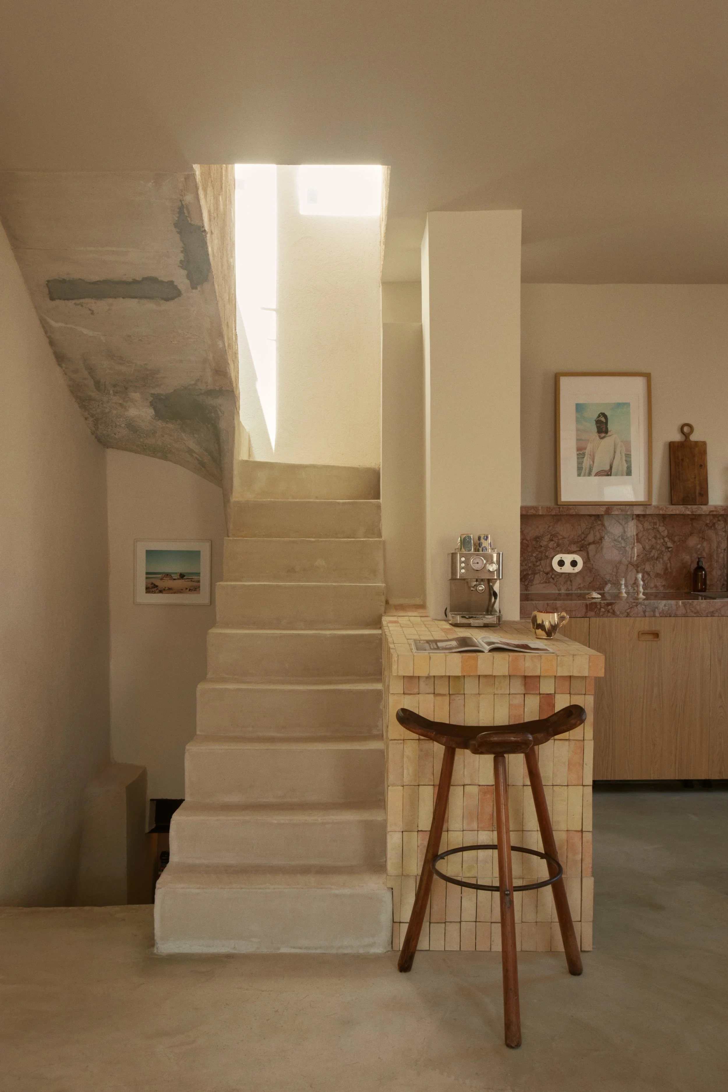 Escalier minéral baigné de lumière naturelle dans une maison rénovée à Marseille par Local Club. Les volumes sobres et les matières brutes créent une architecture intérieure calme et méditative.