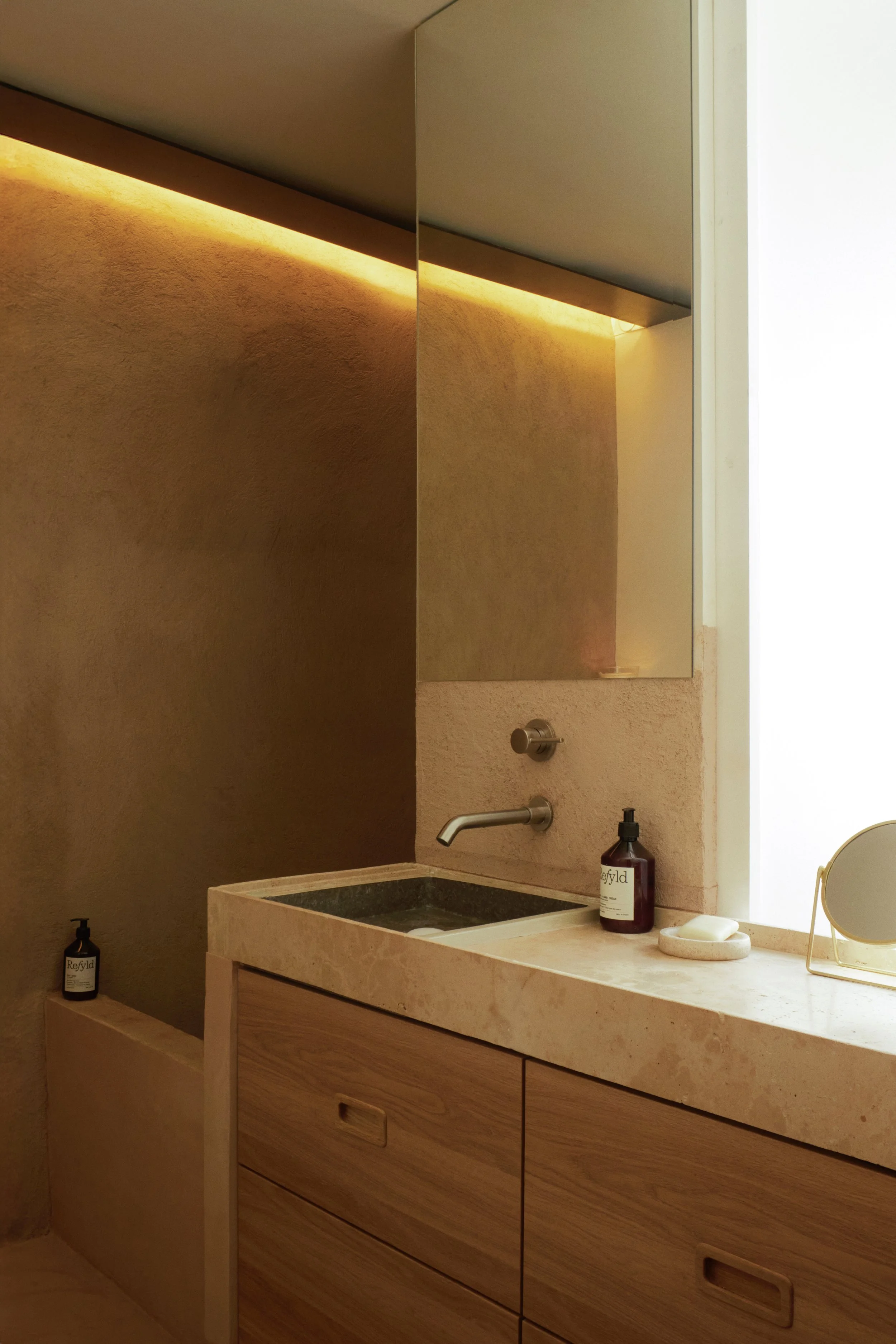 Salle de bain minimaliste conçue par Local Club dans cette maison rénovée à Marseille. Un espace aux tonalités minérales mêlant pierre naturelle, bois sur mesure et enduits texturés dans une ambiance douce, brute et contemporaine.
