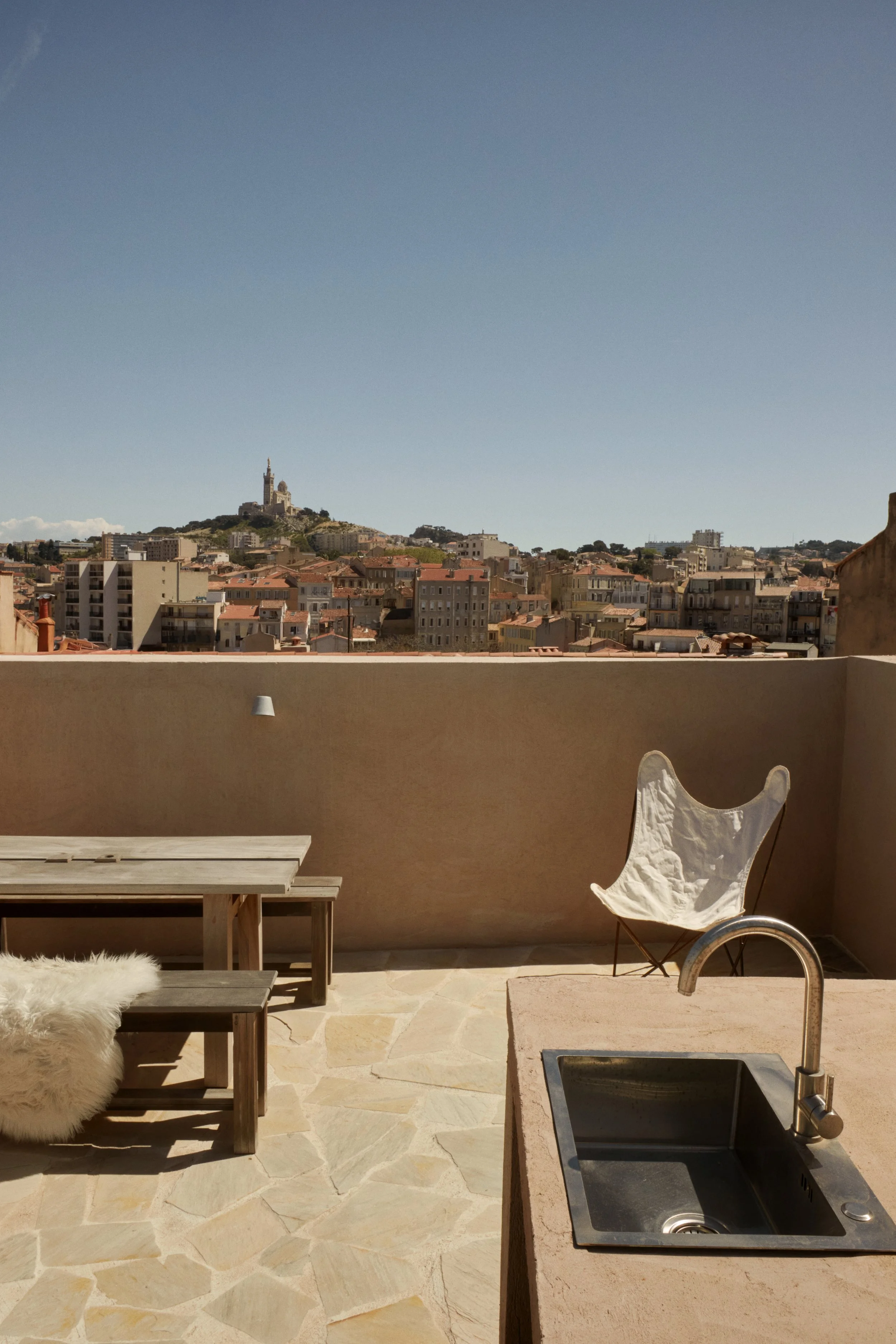 Terrasse de cette maison de ville rénovée à Marseille par Local Club, avec vue sur Notre-Dame de la Garde. Un espace extérieur minimaliste et minéral pensé comme une extension naturelle de l’architecture intérieure, entre lumière du sud et matières b