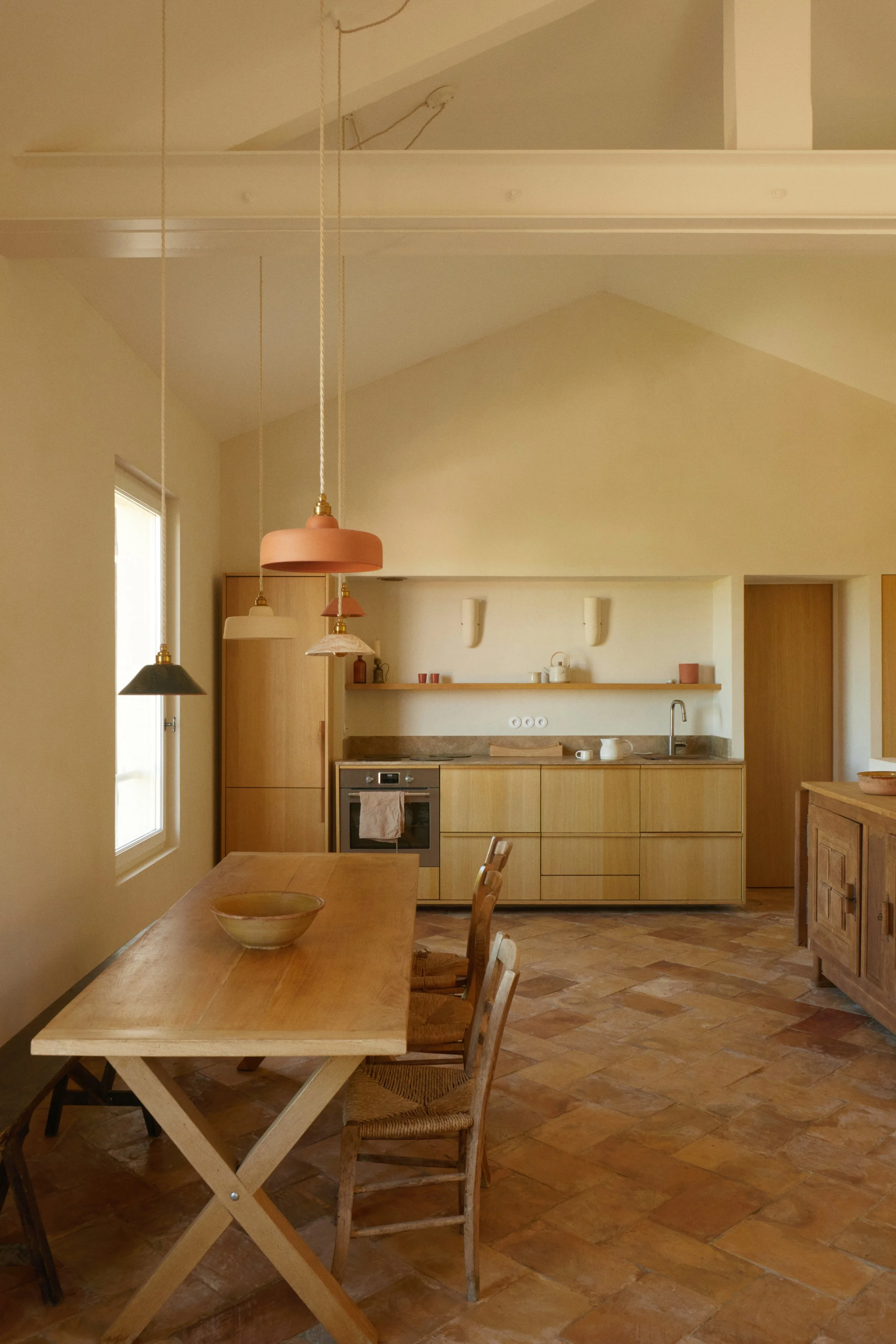 salon d'une maison à cassis tomettes provencales ocre avec table en bois et luminaire en céramique