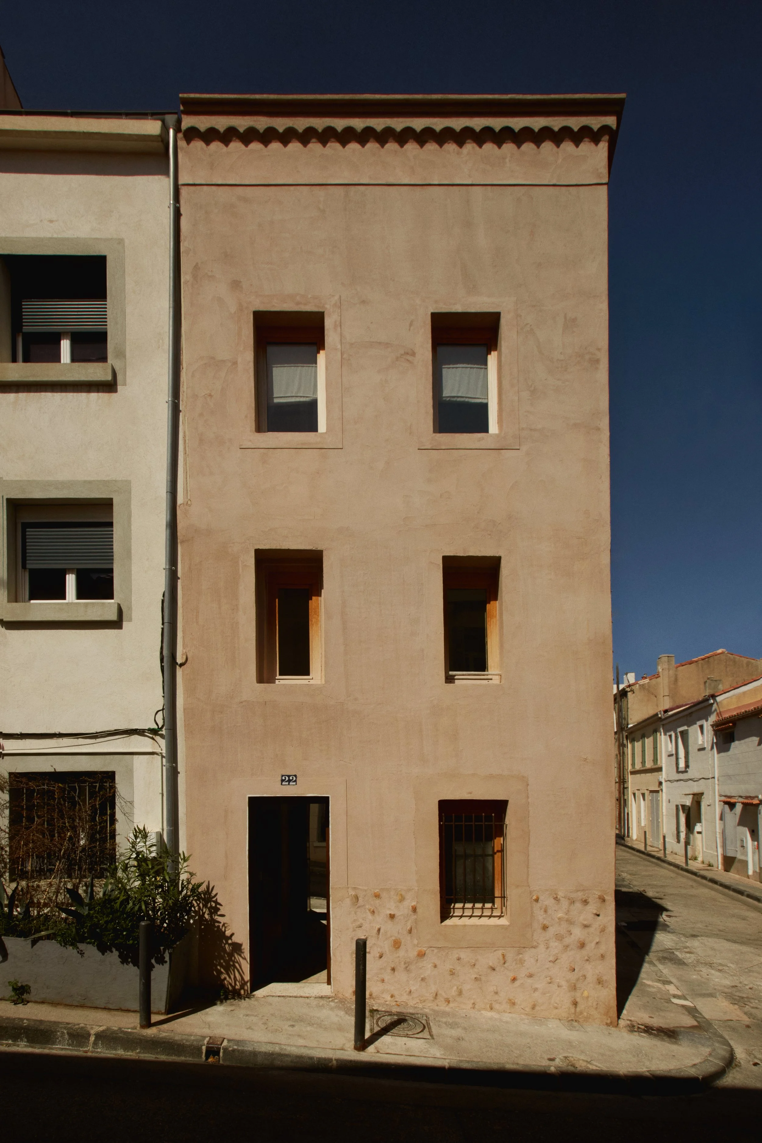 Façade minimaliste d’une maison de ville rénovée à Marseille par Local Club. Une architecture sobre et minérale où les ouvertures, les enduits texturés et les proportions du bâti existant composent une silhouette contemporaine ancrée dans le paysage 