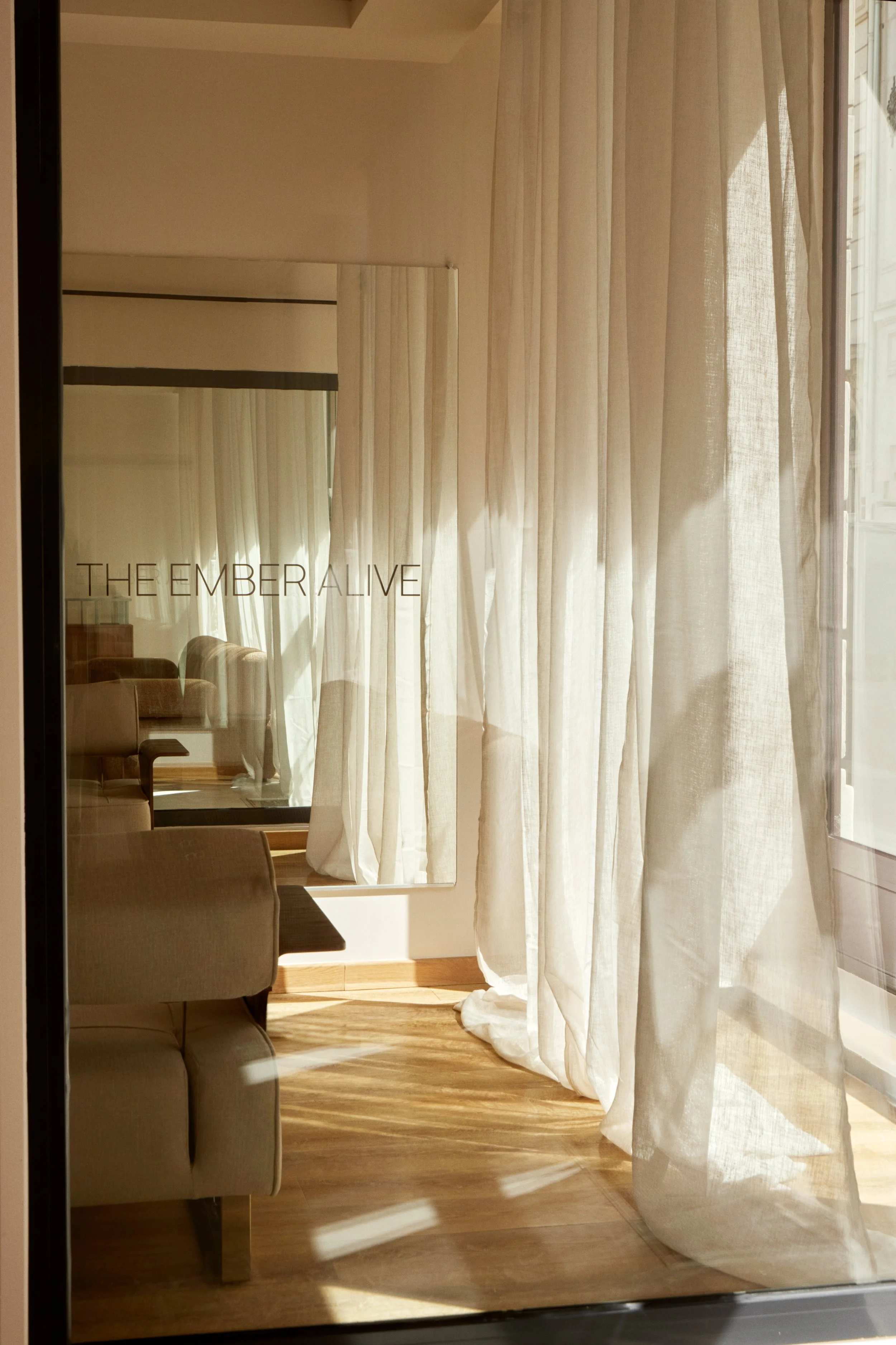 Vitrophanie intérieure, miroir et rideaux lumineux dans un studio wellness parisien, pour une expérience client douce et enveloppante.