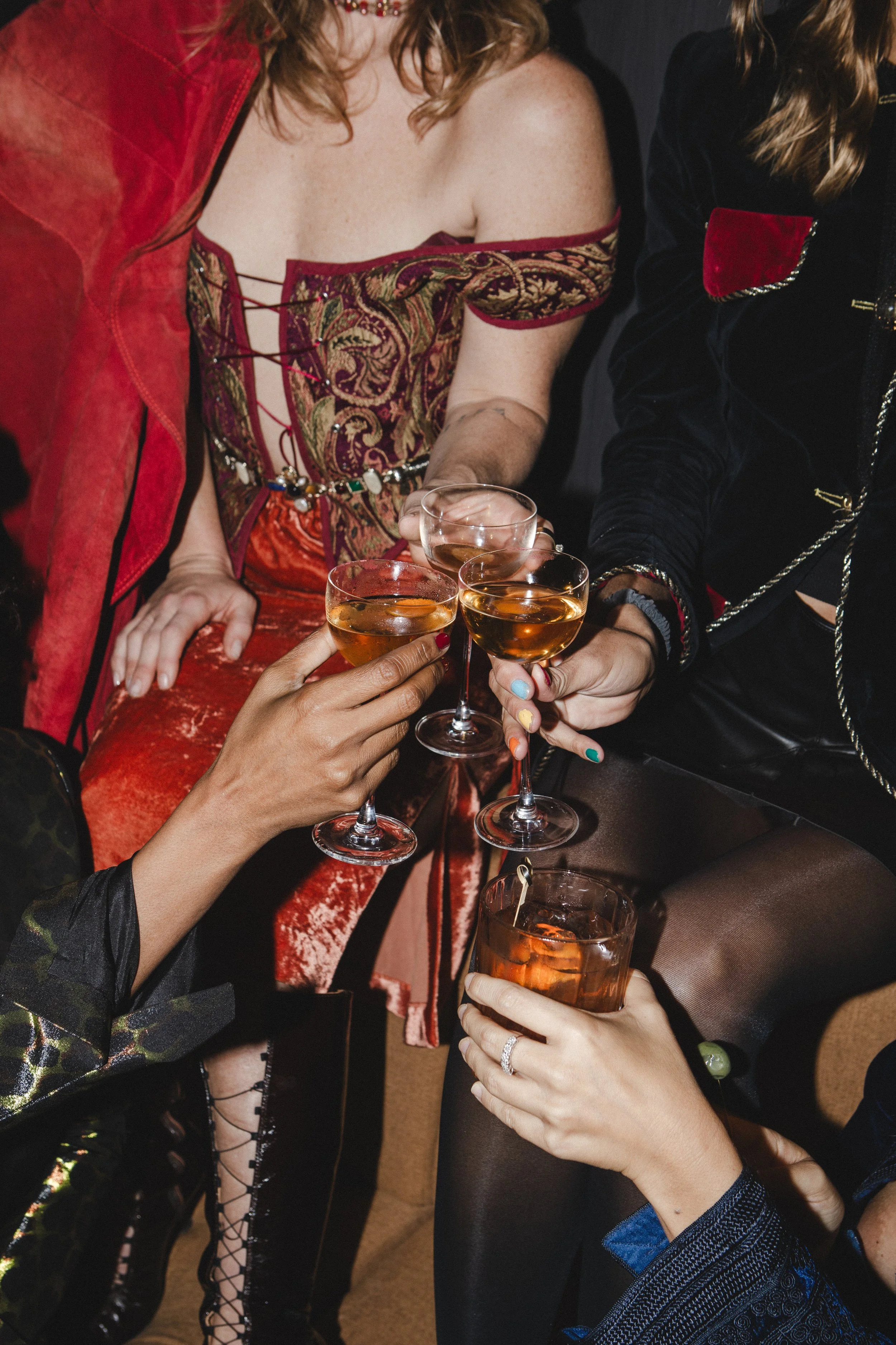 Group of women celebrating with cocktails, holding glasses filled with champagne or sparkling wine, in a festive setting.
